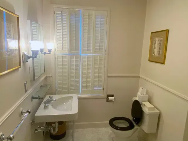 Accessible bathroom with sink, grab bars, toilet, and shower bench by a window