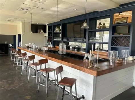 Empty bar with wooden stools, a navy blue backdrop, and a copper-toned counter.
