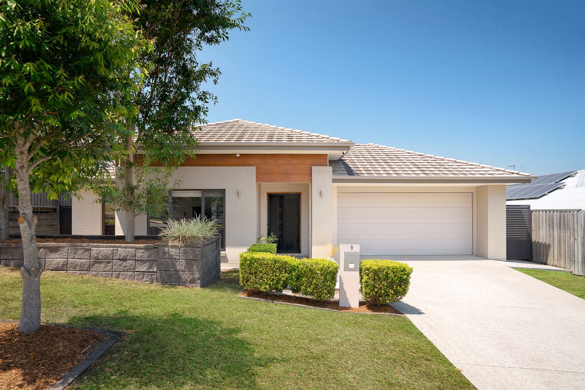 A large white house with a gray garage door and stairs leading up to it.