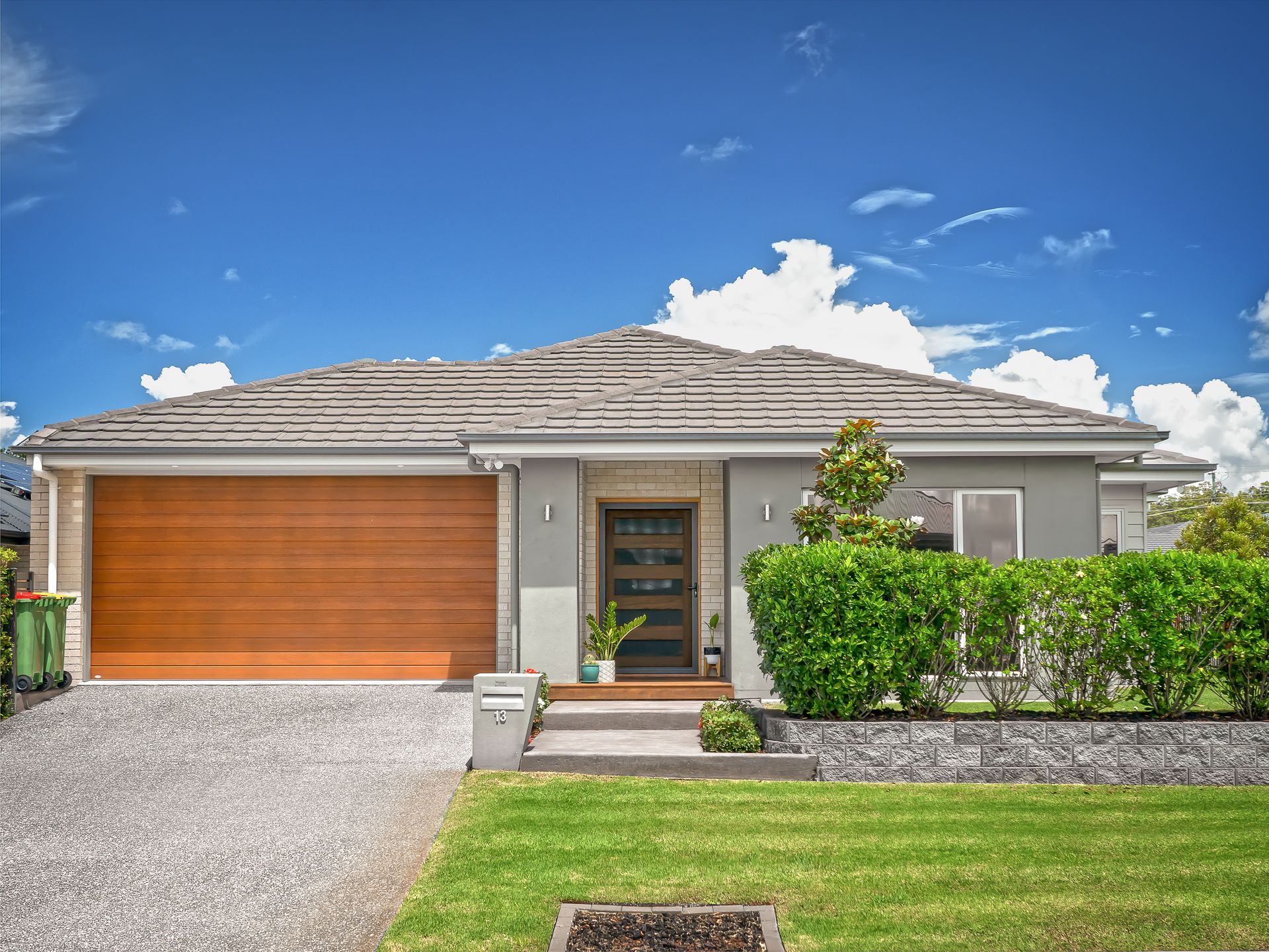 A white house with a wooden door and a concrete driveway.