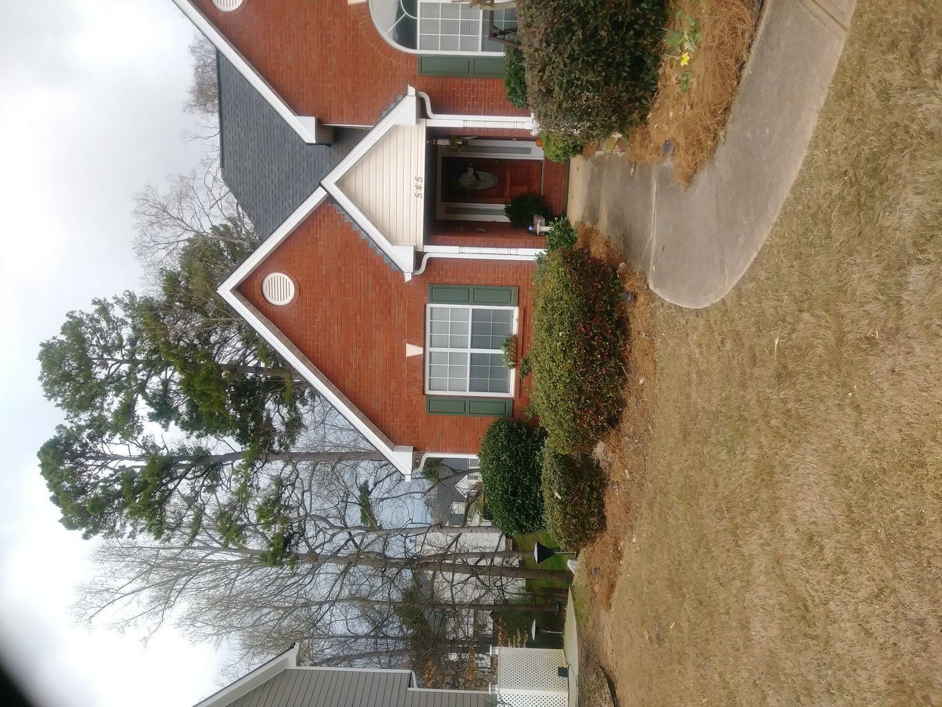 Red brick house with white trim, black roof, and walkway.