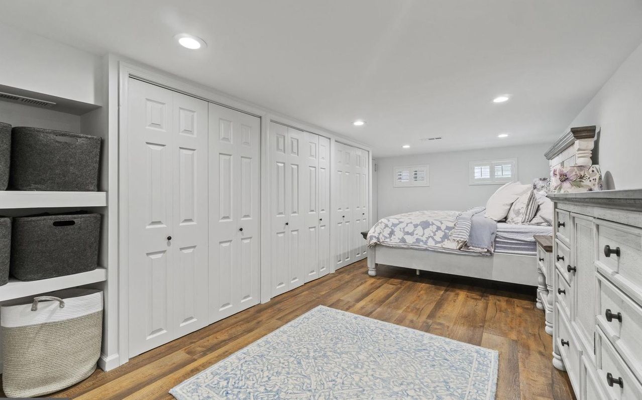 A bedroom with a bed , dresser , and closets.
