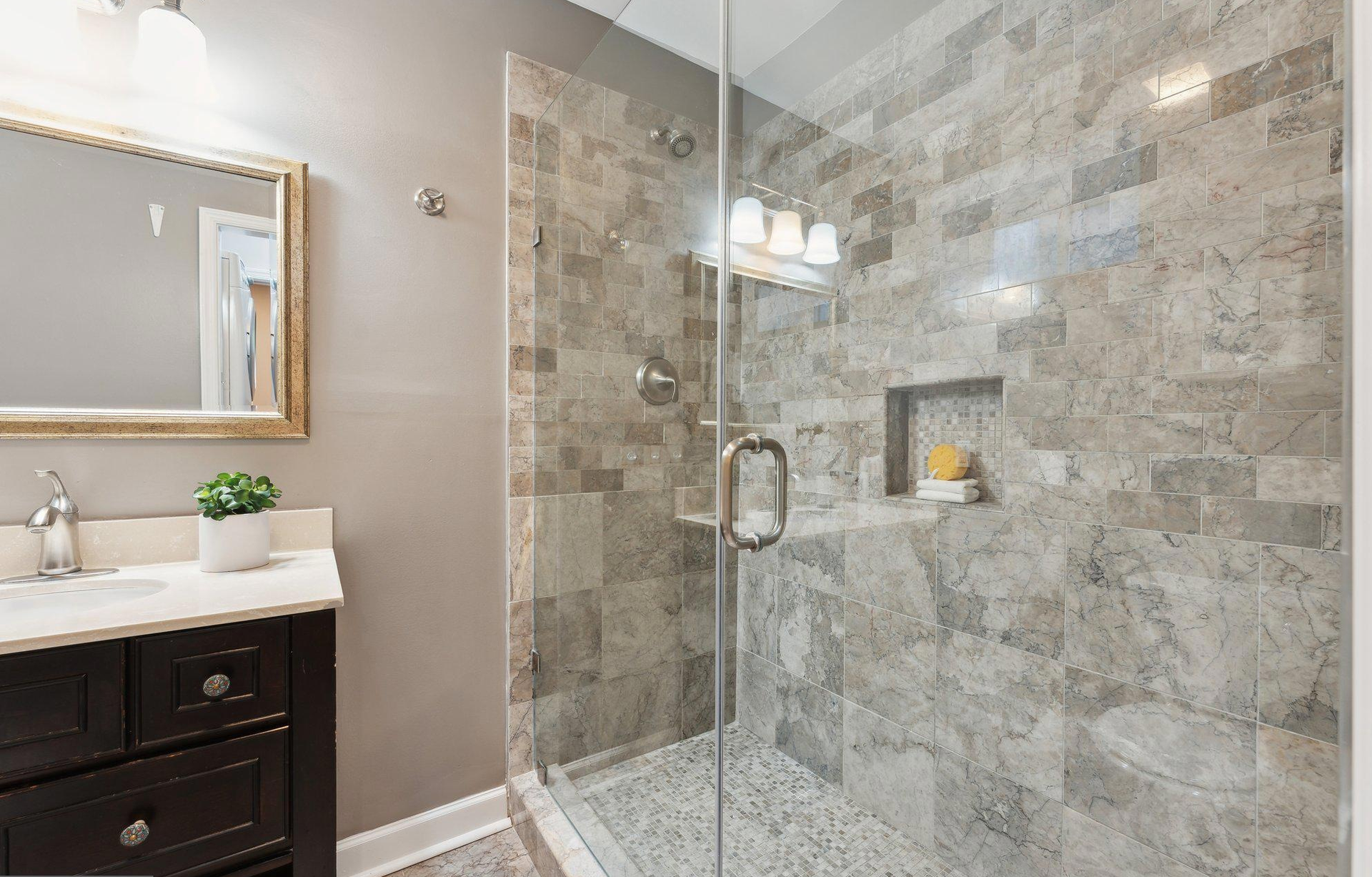 A bathroom with a walk in shower , sink and mirror.