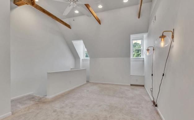 An empty room with a ceiling fan and a window.
