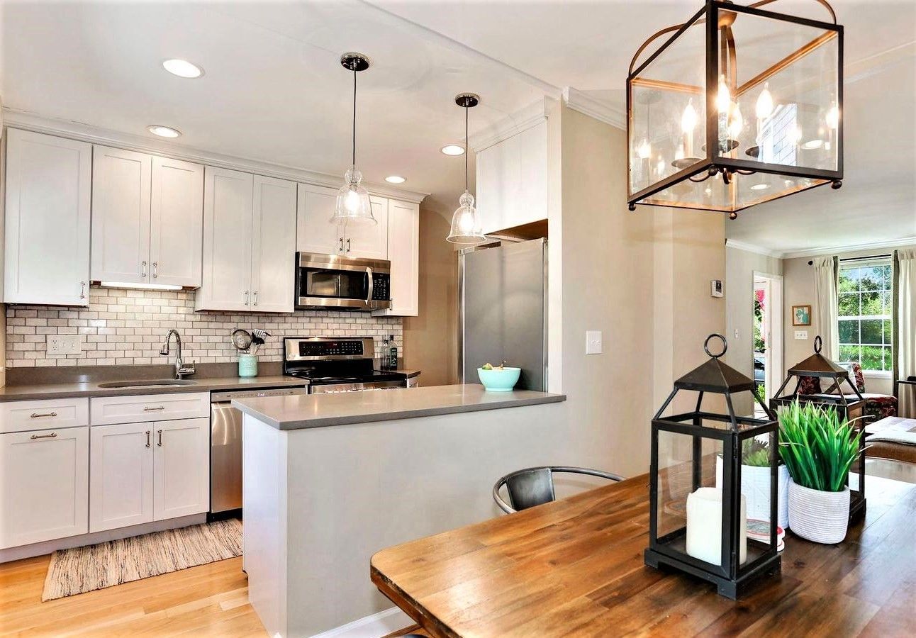 A kitchen with white cabinets and stainless steel appliances and a wooden table.