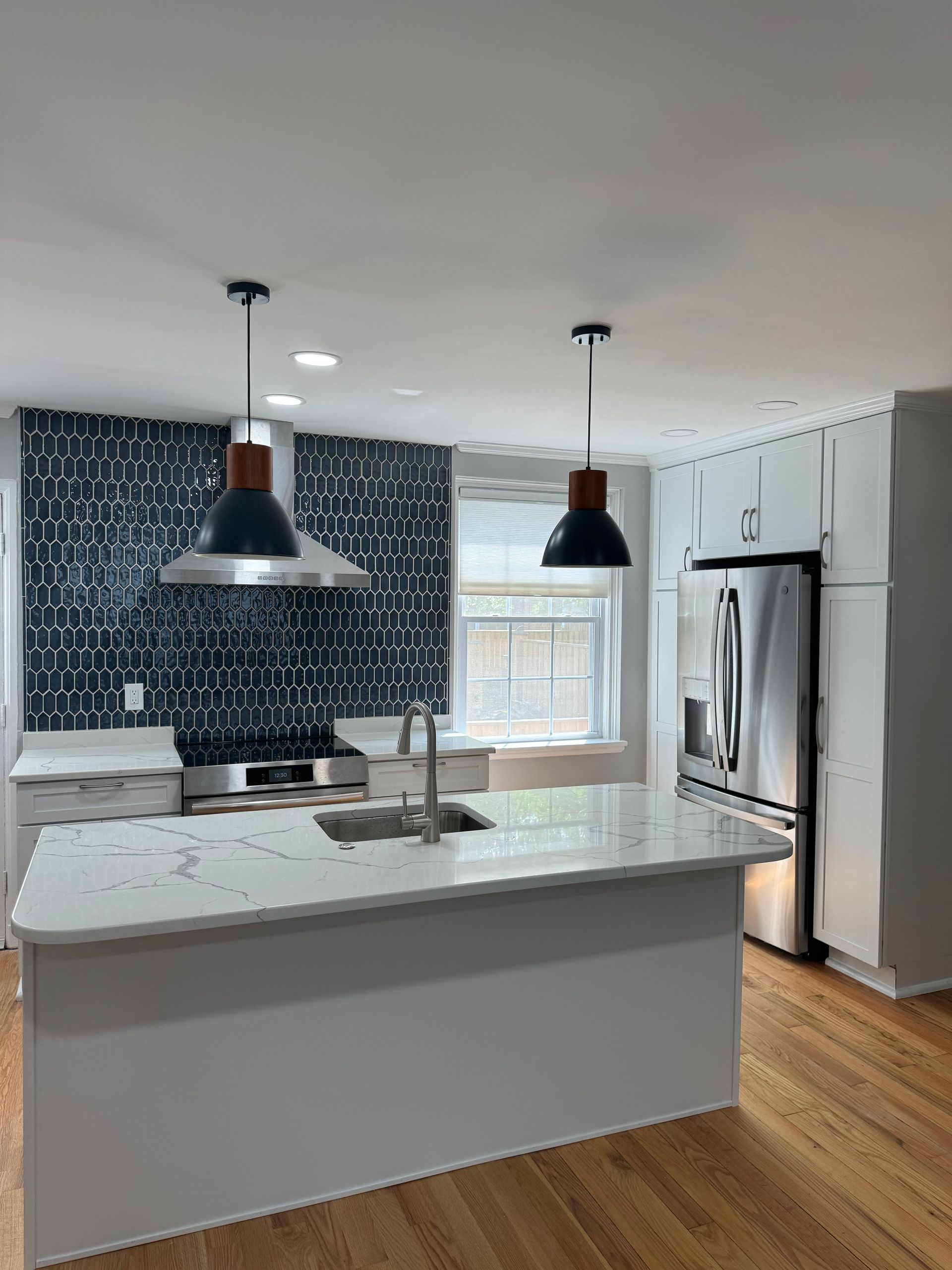 A kitchen with a large island , sink , refrigerator and stainless steel appliances.