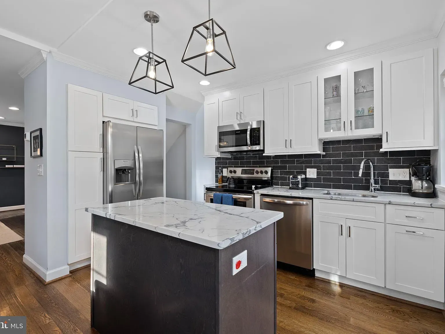 A kitchen with white cabinets , stainless steel appliances and a large island.