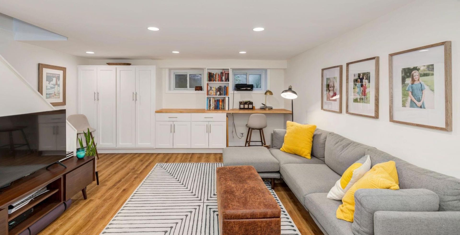 A living room with a couch , ottoman , and television.