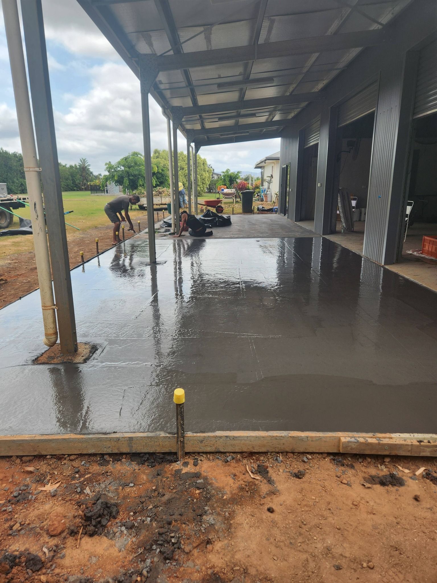 Workers Finishing a Concrete Pour Under a Covered Area — Sun Co Concrete And Construction in Dimbulah, QLD