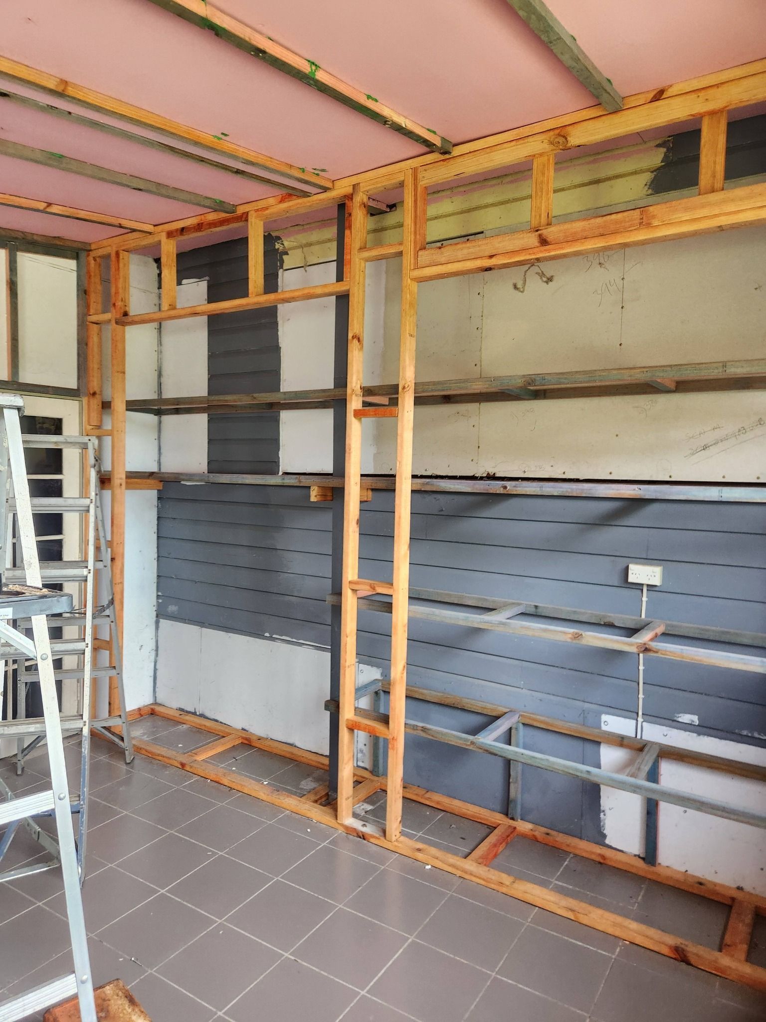 Man on Ladder Building Wooden Wall, Using a Drill Inside a Building — Sun Co Concrete And Construction in Dimbulah, QLD