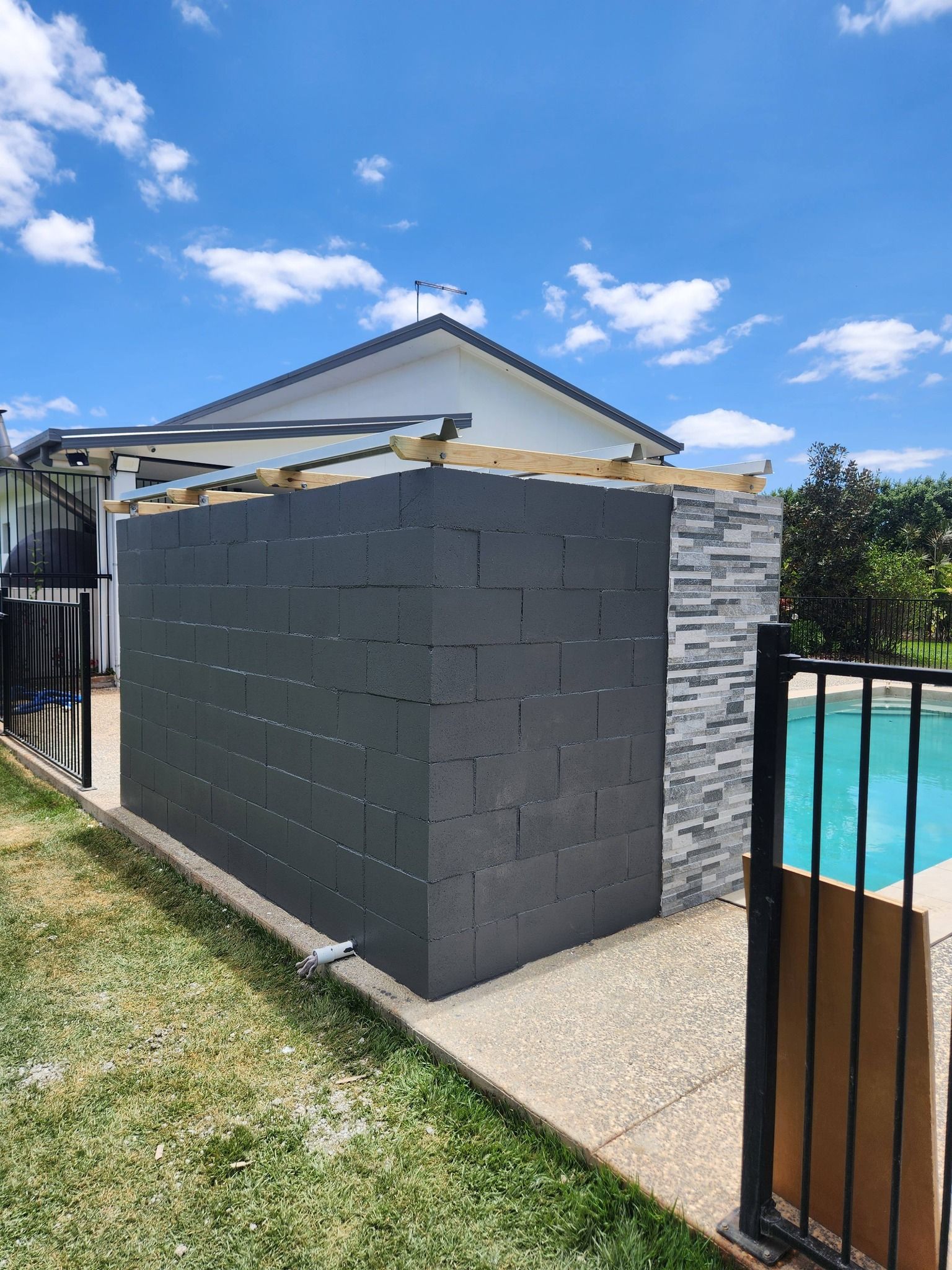 Gray Block Wall With a Stone Side, Next to a Swimming Pool — Sun Co Concrete And Construction in Dimbulah, QLD