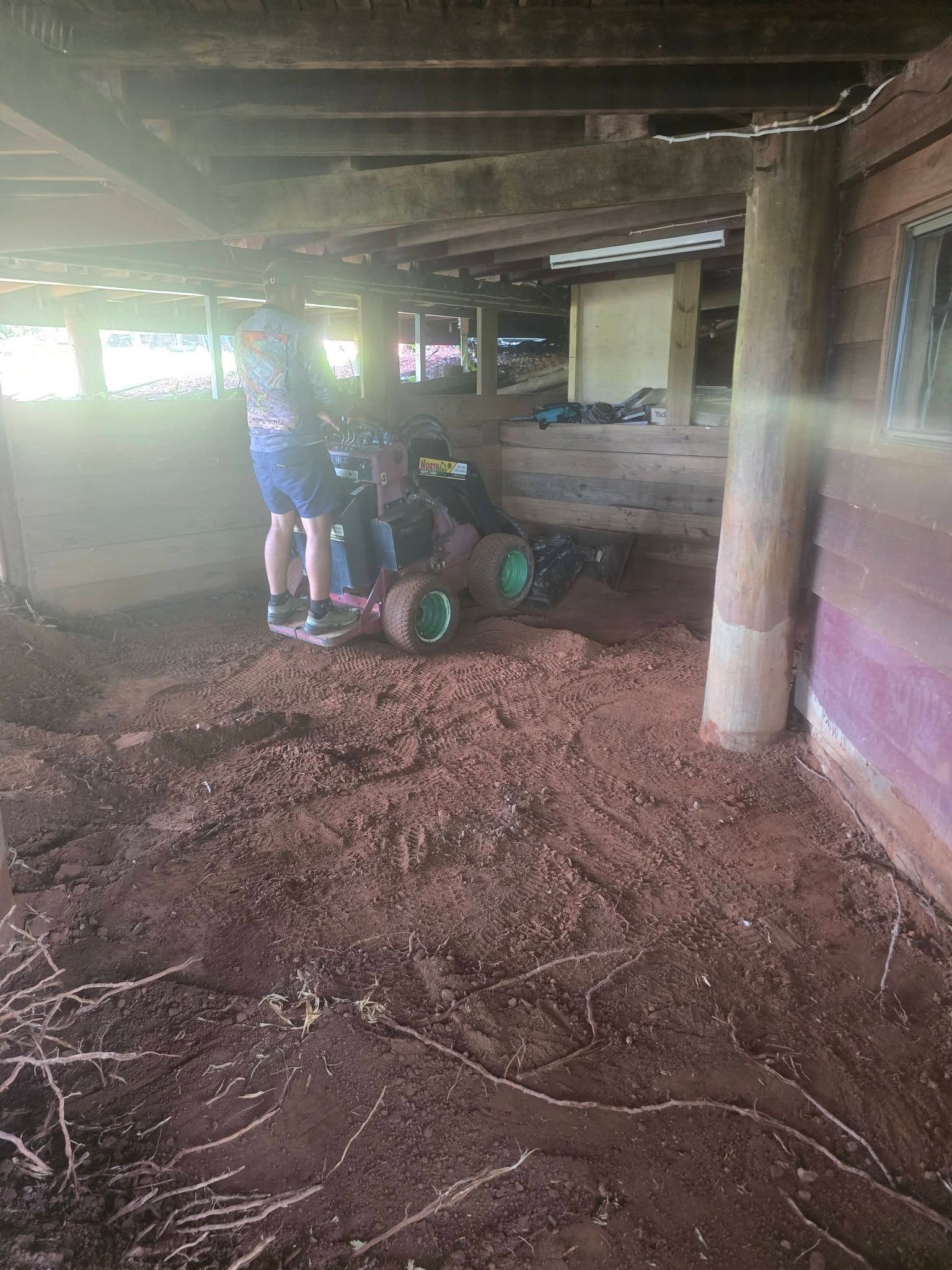 People Moving a Large Object With Green Wheels in a Dirt-floored Shed — Sun Co Concrete And Construction in Dimbulah, QLD