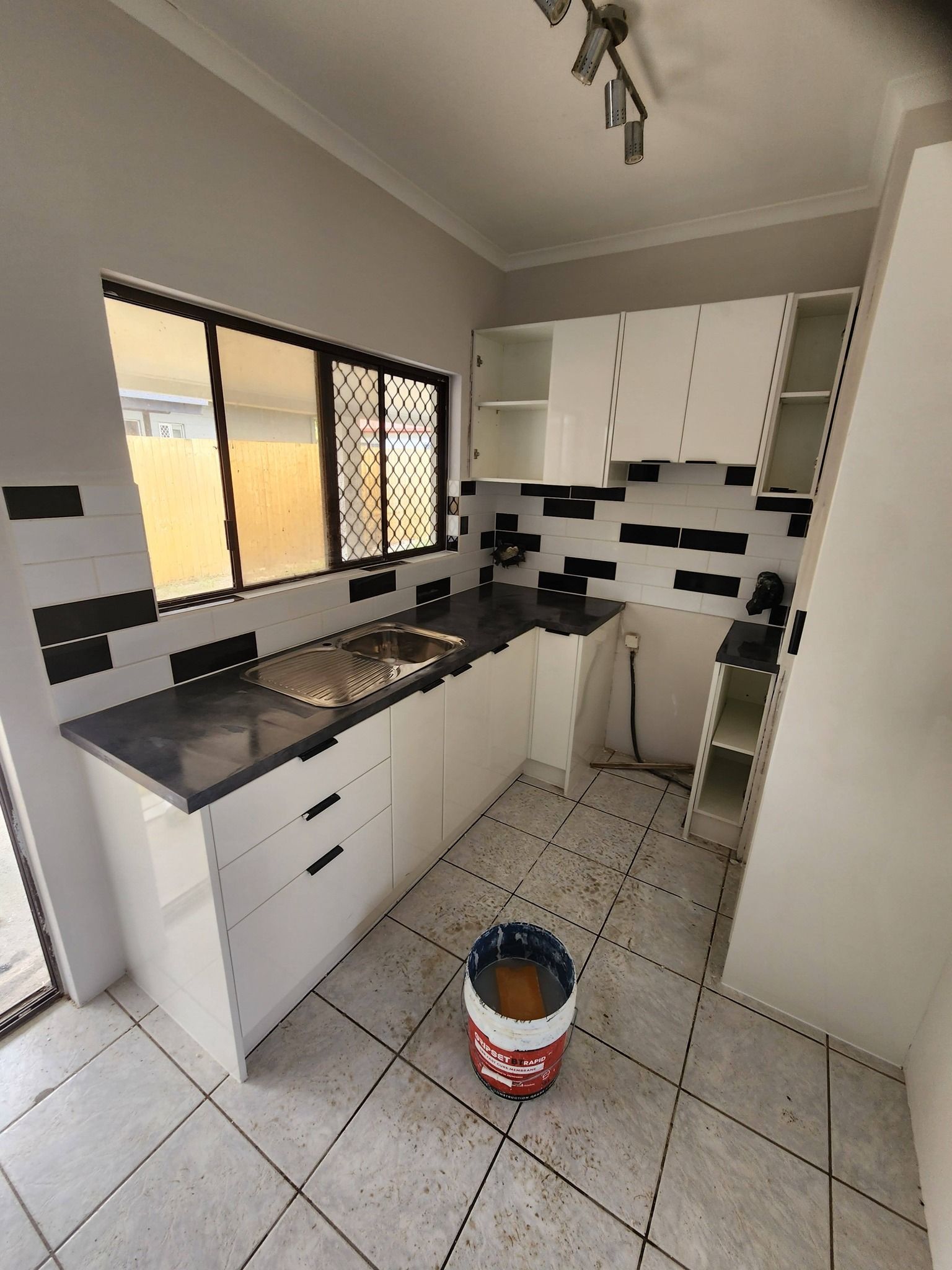 Small Kitchen With White Cabinets, Dark Countertops — Sun Co Concrete And Construction in Dimbulah, QLD