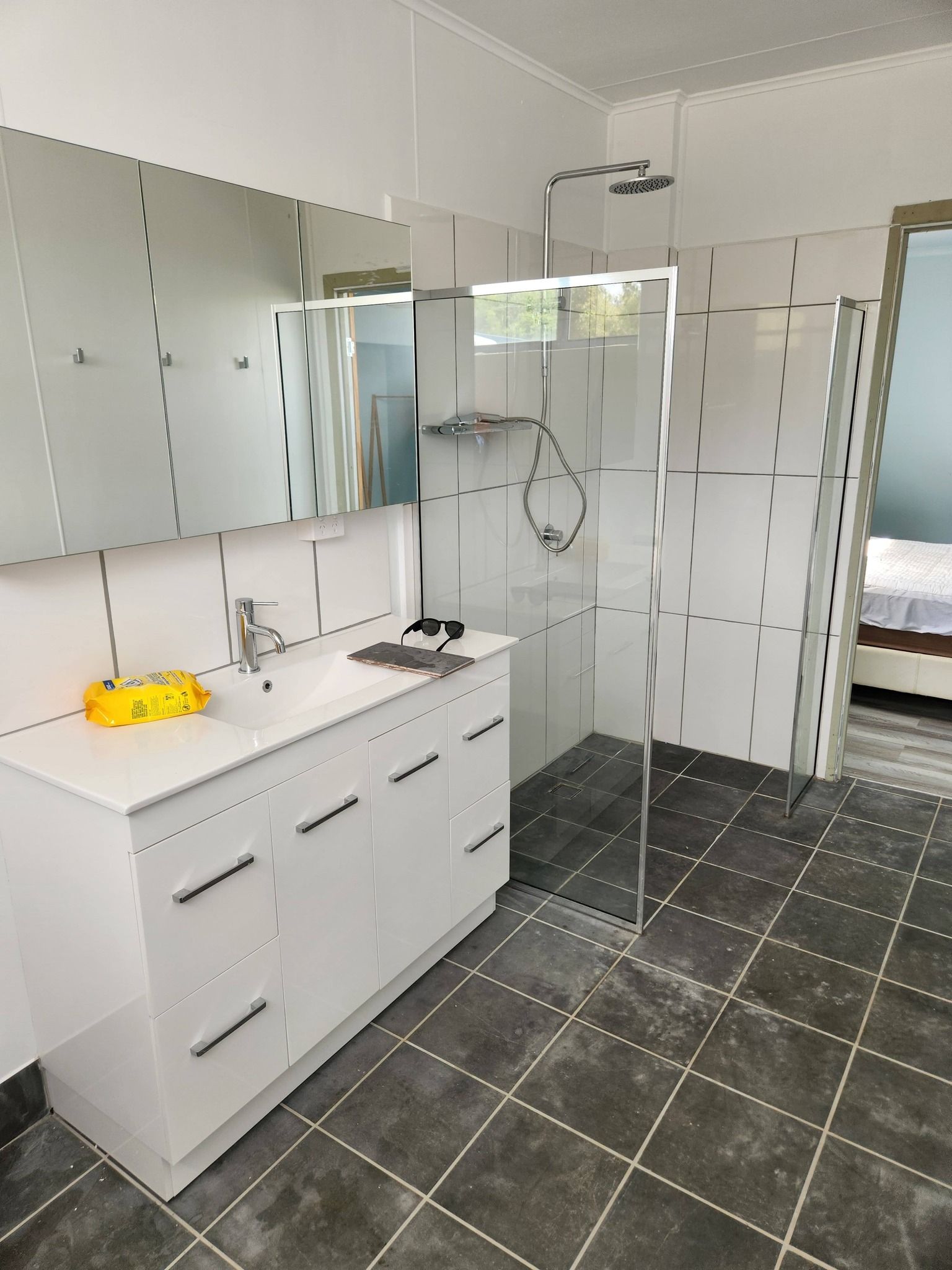 White Bathroom With Glass Shower, White Vanity, Floor, and Large Mirror — Sun Co Concrete And Construction in Dimbulah, QLD