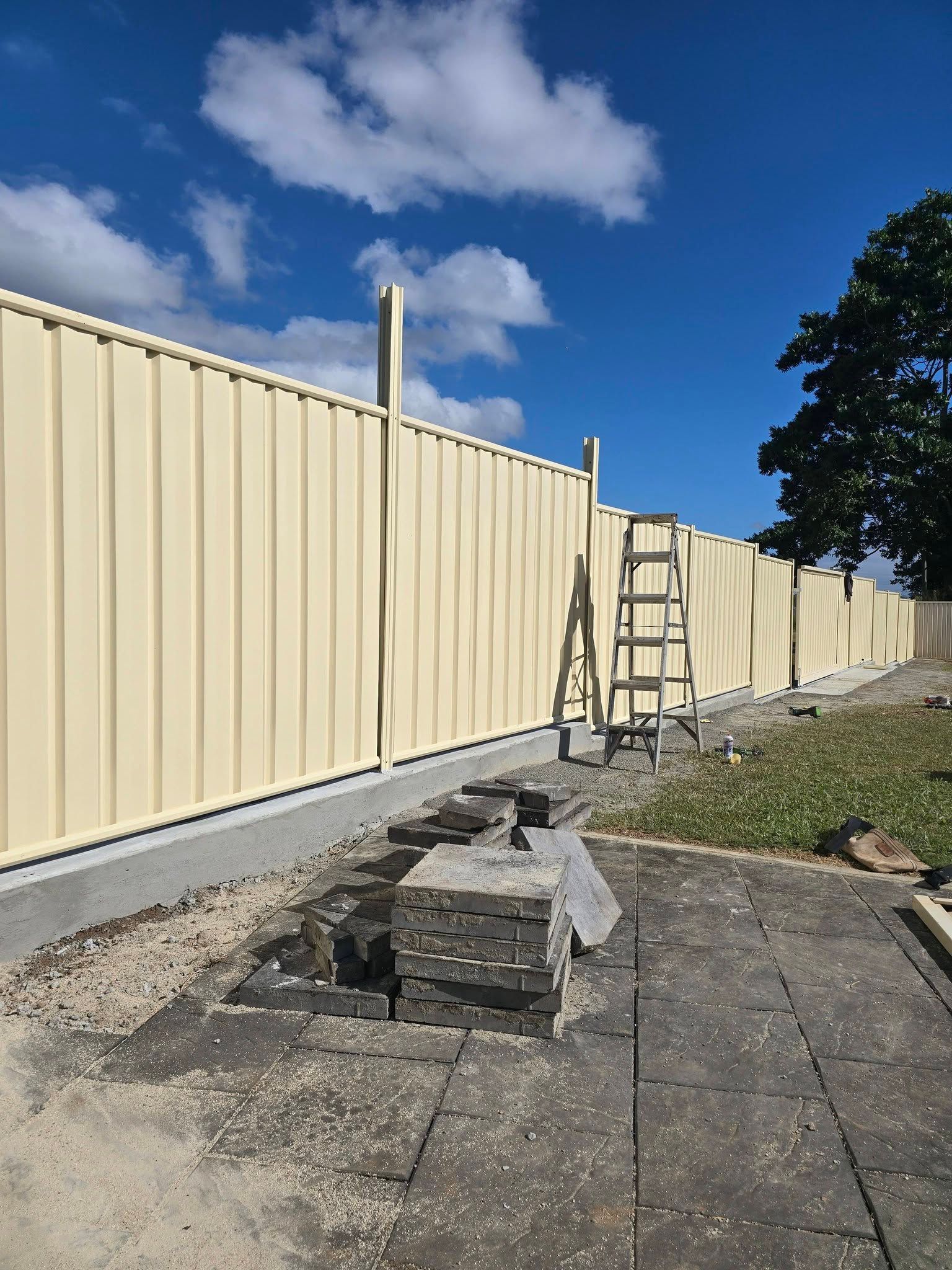 Metal Fence Under Construction With Ladder and Exposed Concrete Base — Sun Co Concrete And Construction in Dimbulah, QLD
