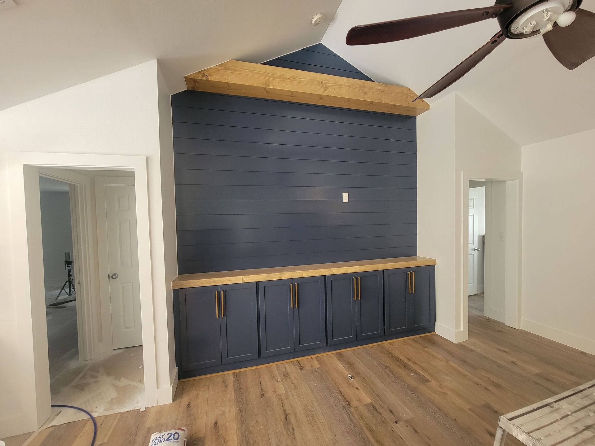 A close-up of a kitchen island with an open oak drawer, featuring dark metal hardware and a concrete countertop.