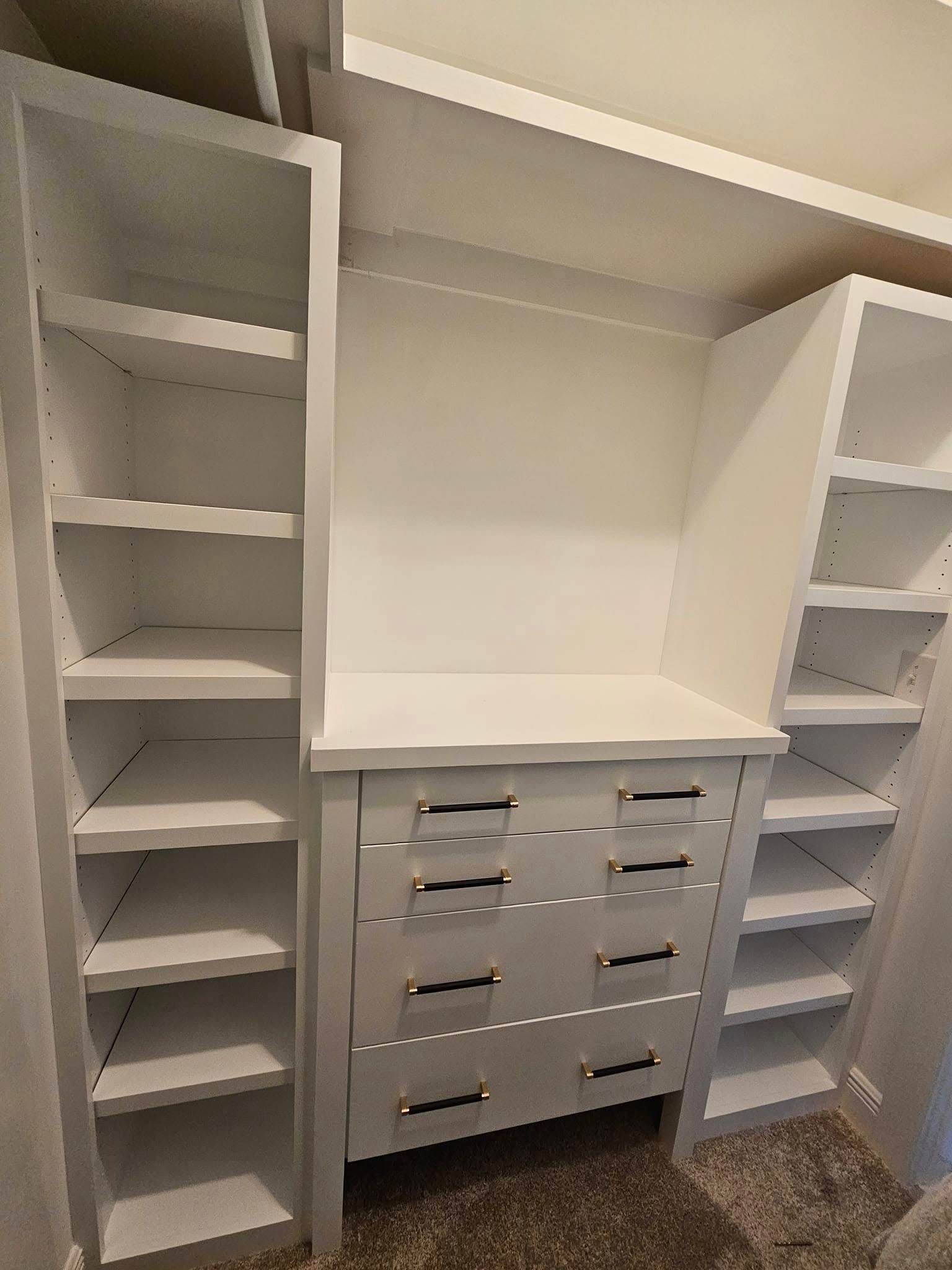 Walk-in closet with white cabinetry, wooden floors, a central island with a granite top, and organized hanging clothes.