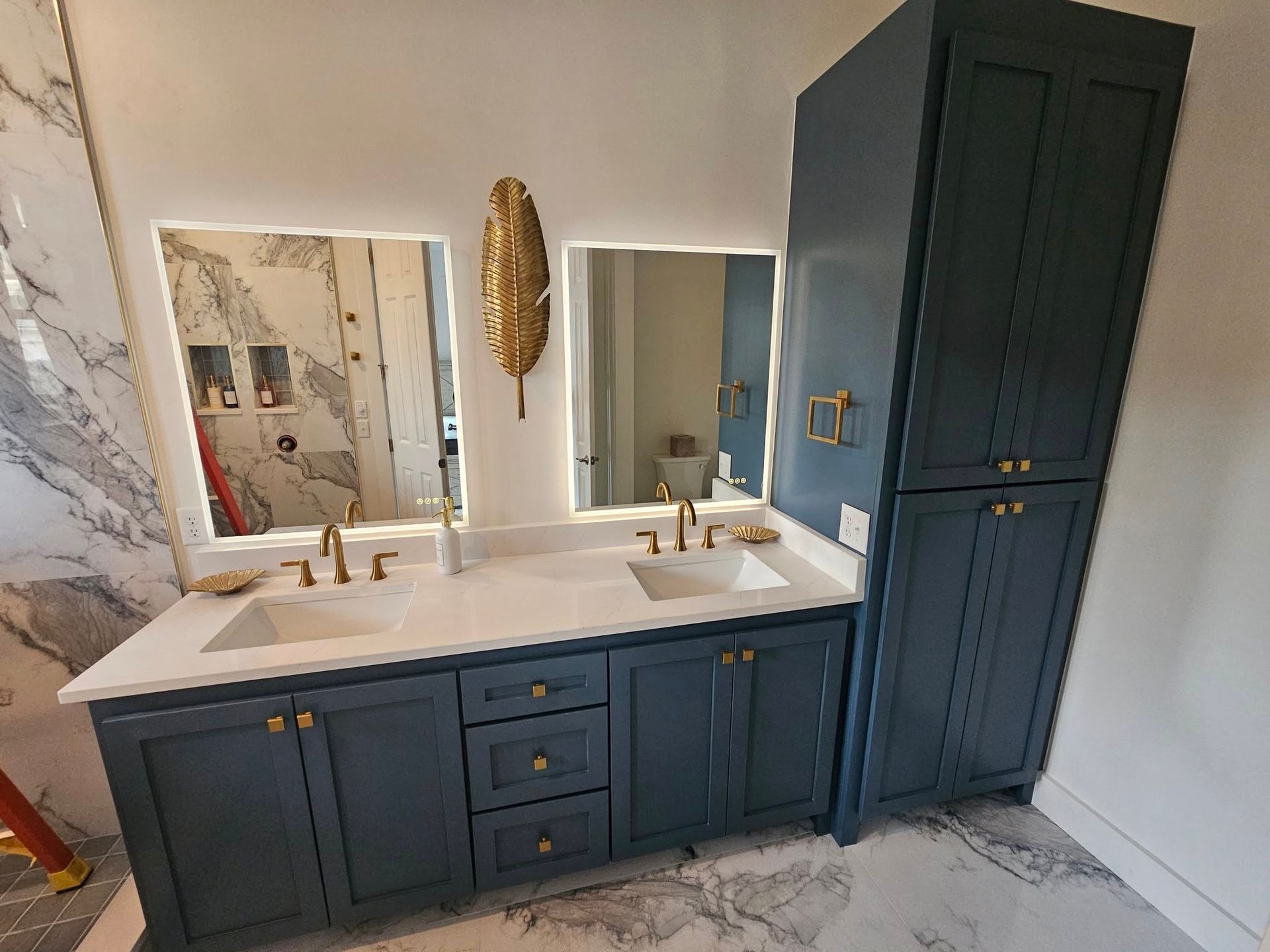 Modern white bathroom with double vanity, gold fixtures, circular mirrors, and a glass-enclosed walk-in shower.