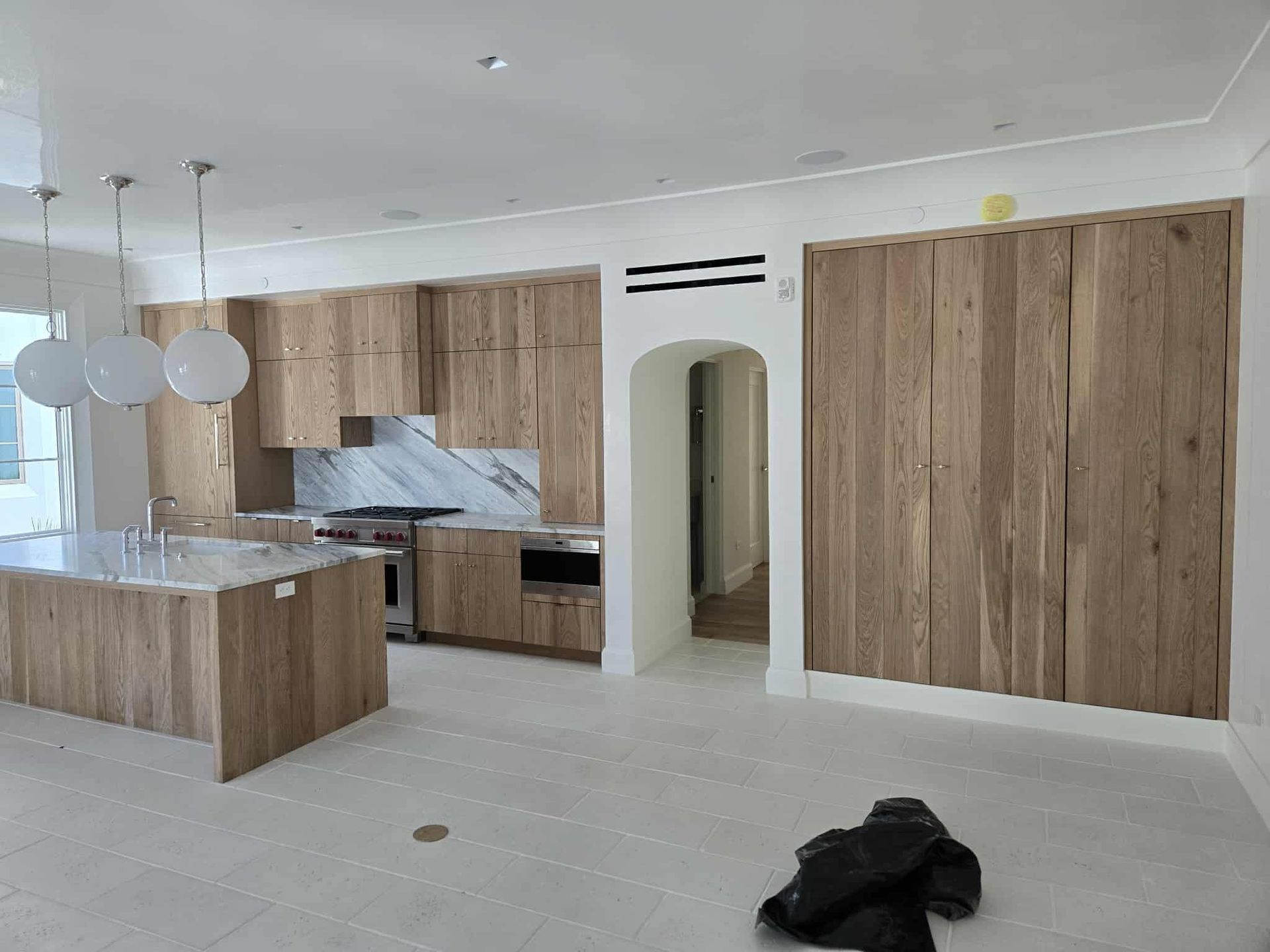 A modern kitchen featuring light grey shaker-style cabinets, white countertops, and a built-in gas stove.
