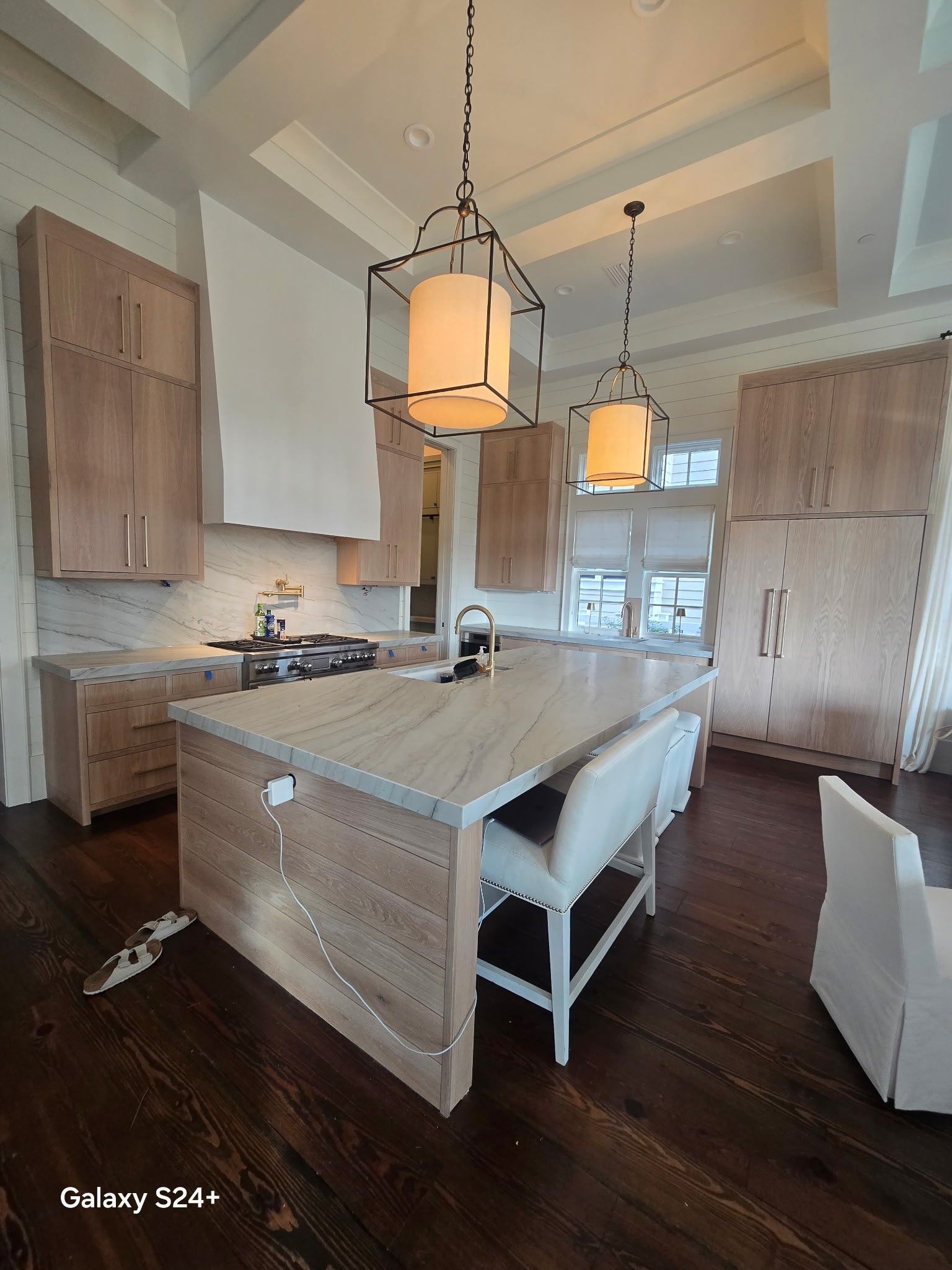 A modern kitchen featuring white cabinets, stainless steel oven, and wood-patterned flooring.