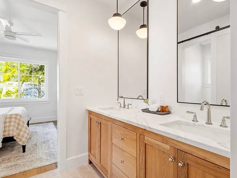 Modern bathroom vanity with a chevron-tiled backsplash, two mirrors, dark cabinetry, and gold hardware.