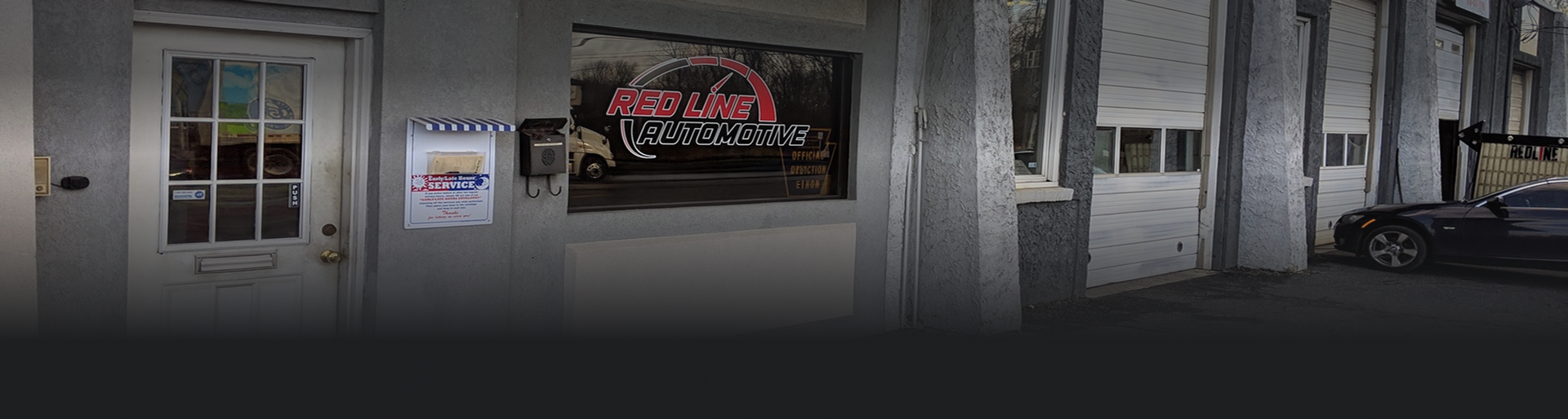 Exterior of an auto repair shop with a car in front of the garage doors | Redline Automotive