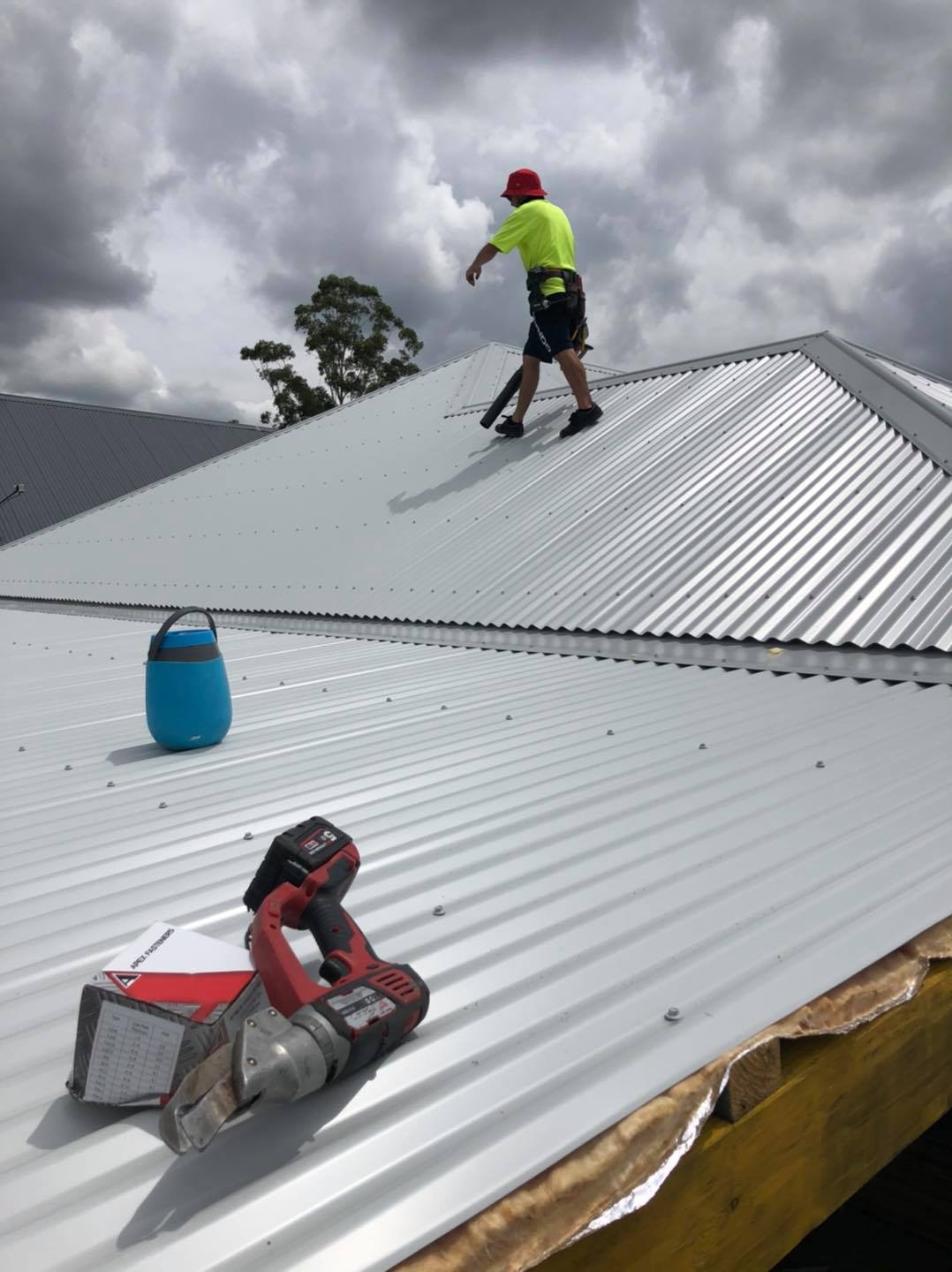 A man is standing on top of a metal roof.