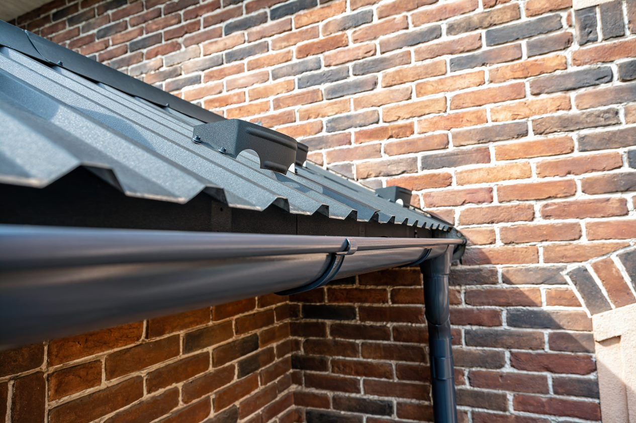 A close up of a gutter on a brick wall.