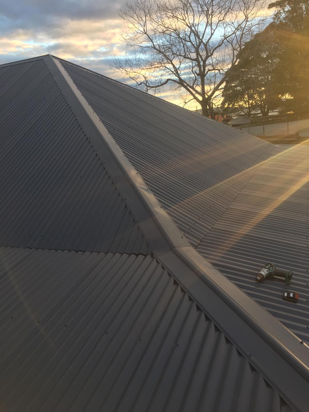 A close up of a roof with a sunset in the background.