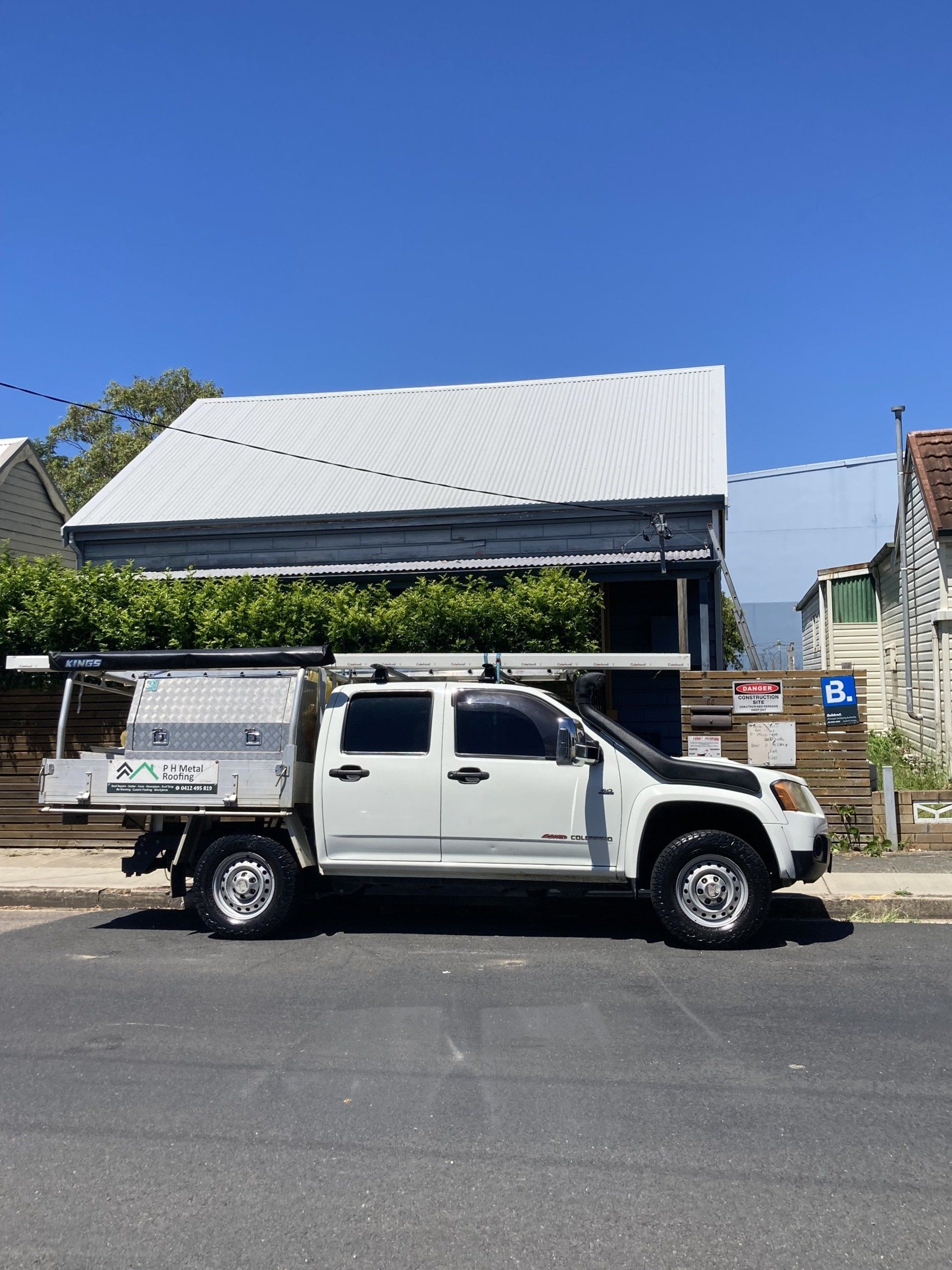 A white truck is parked on the side of the road in front of a house.