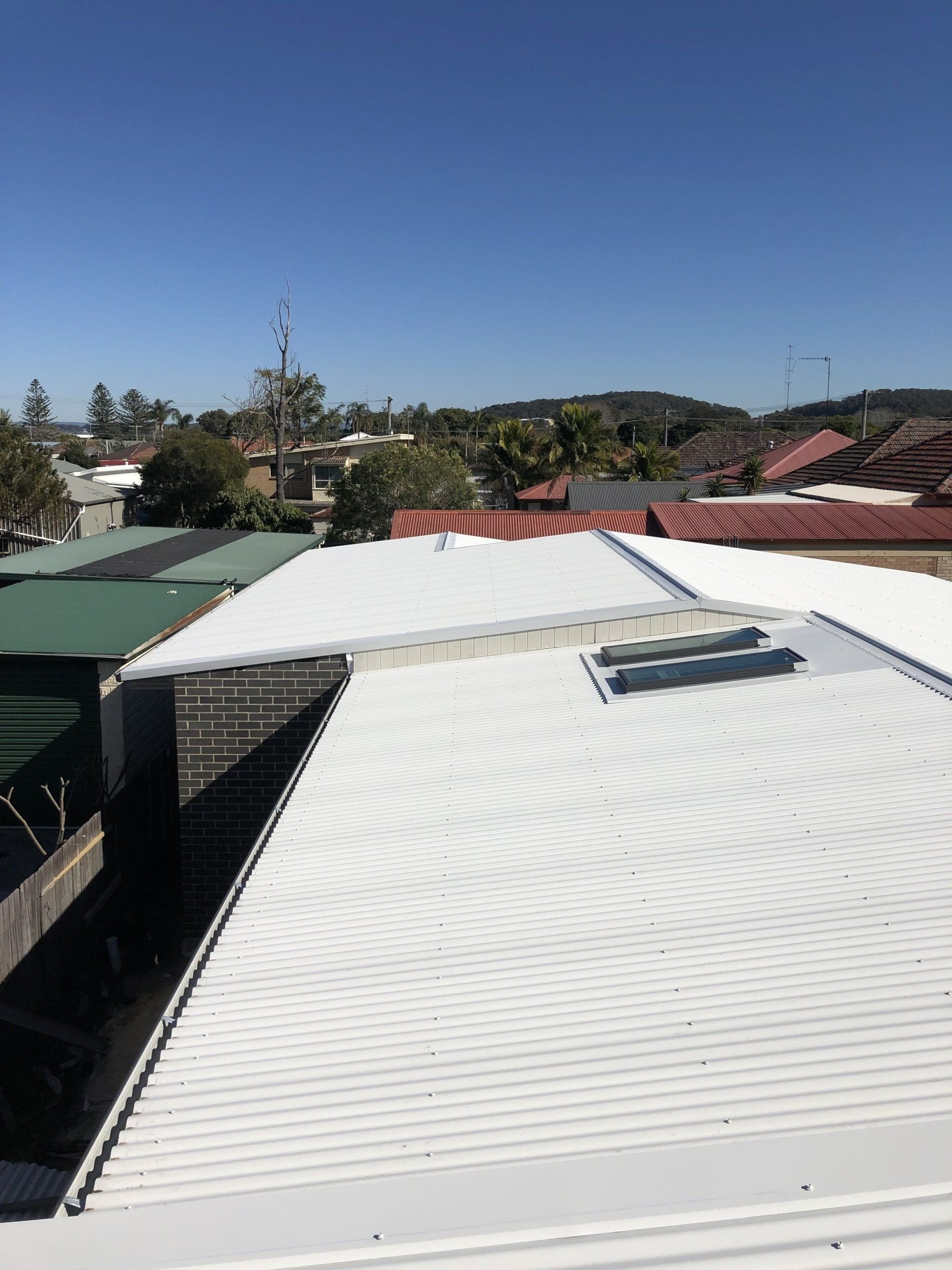 A white roof with a skylight on it is sitting on top of a building.