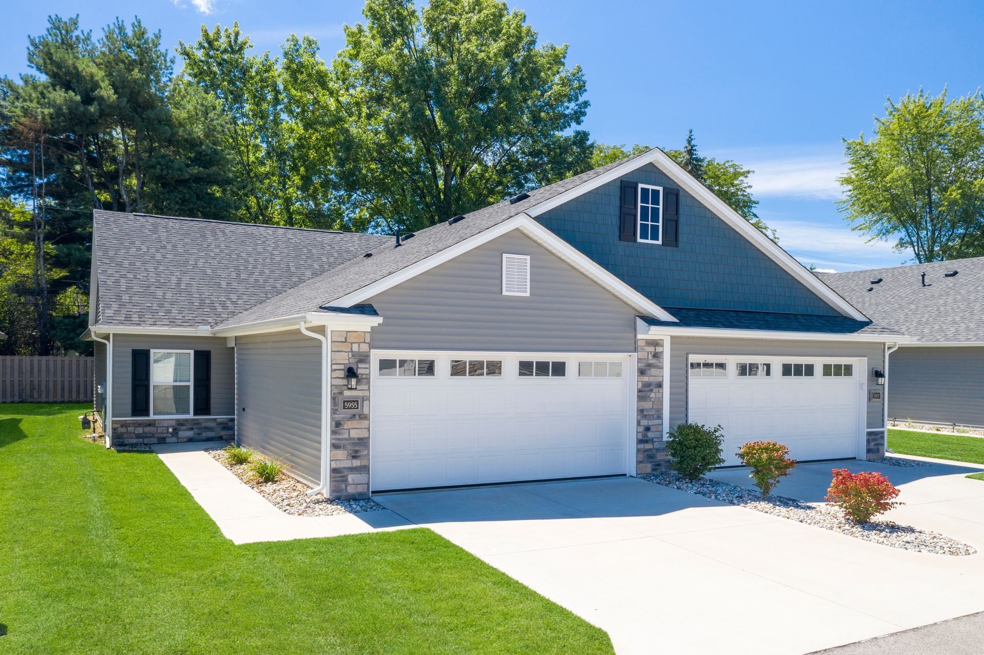 Photo of a duplex with garages and driveways, as well as a home entrance in view