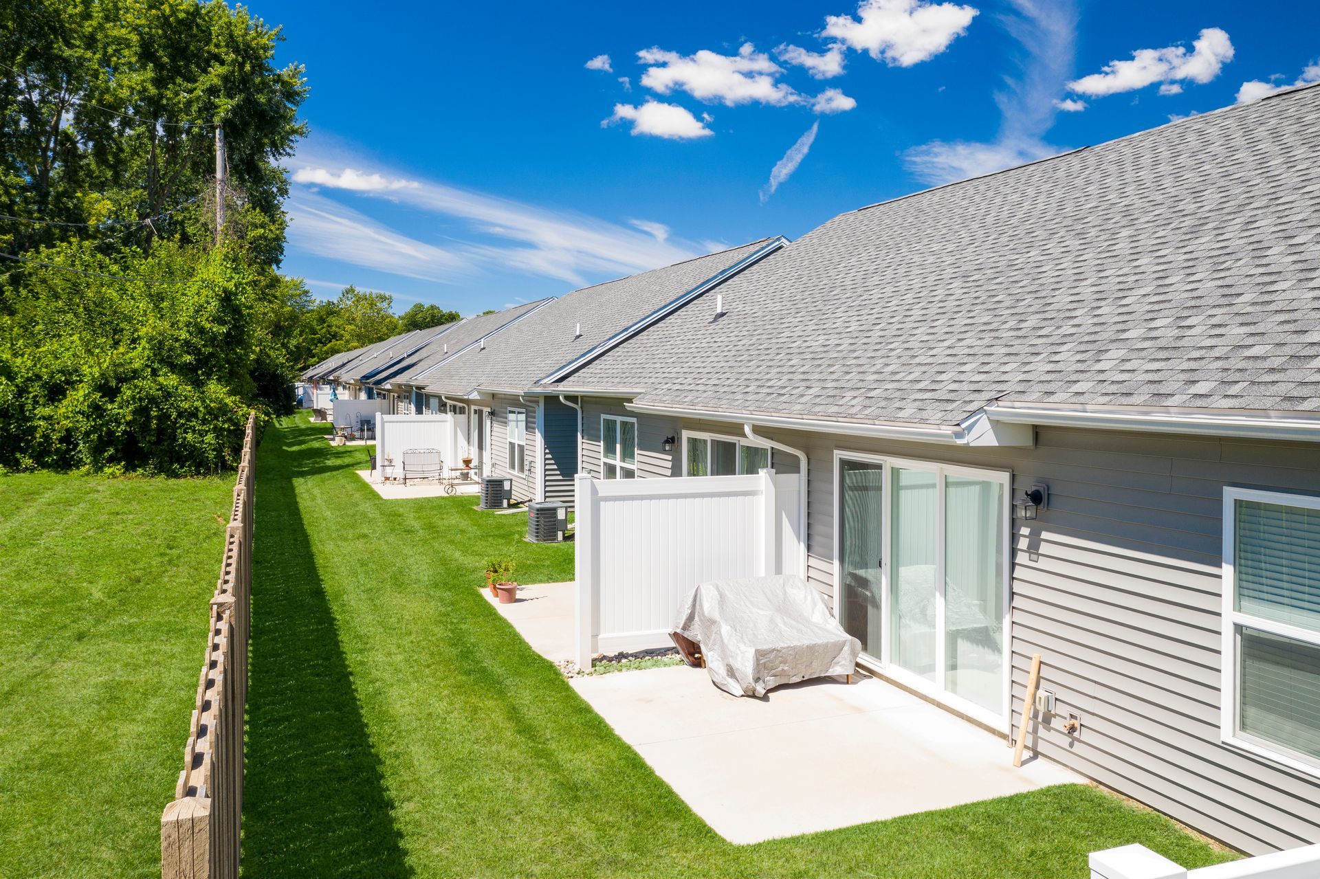 Photo of the backyards in a row of duplexes, with a long fence running the span of the property