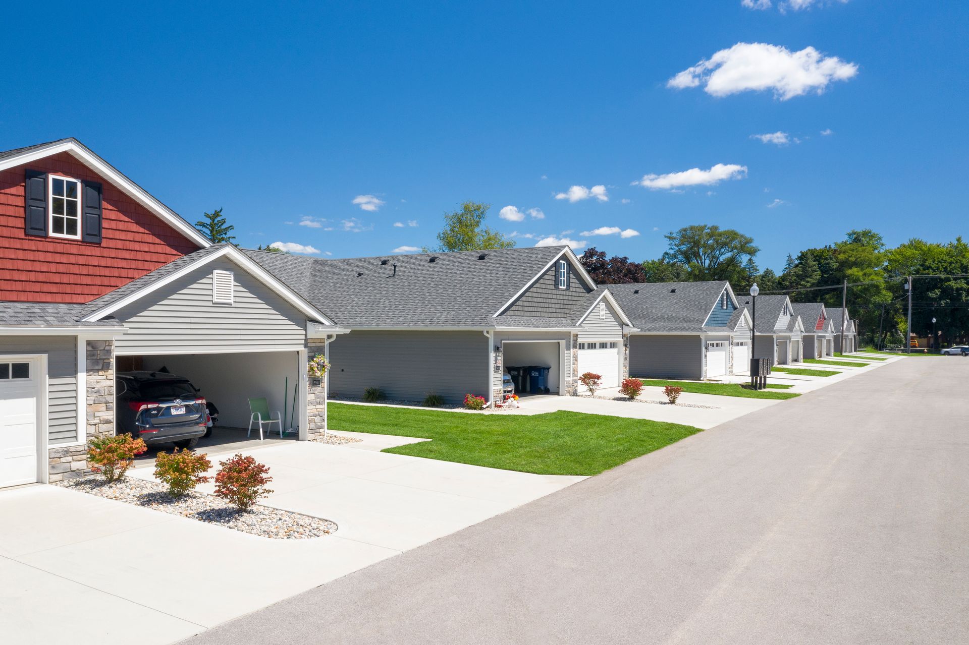 Photo of a row of duplexes, a few homes have their garage open