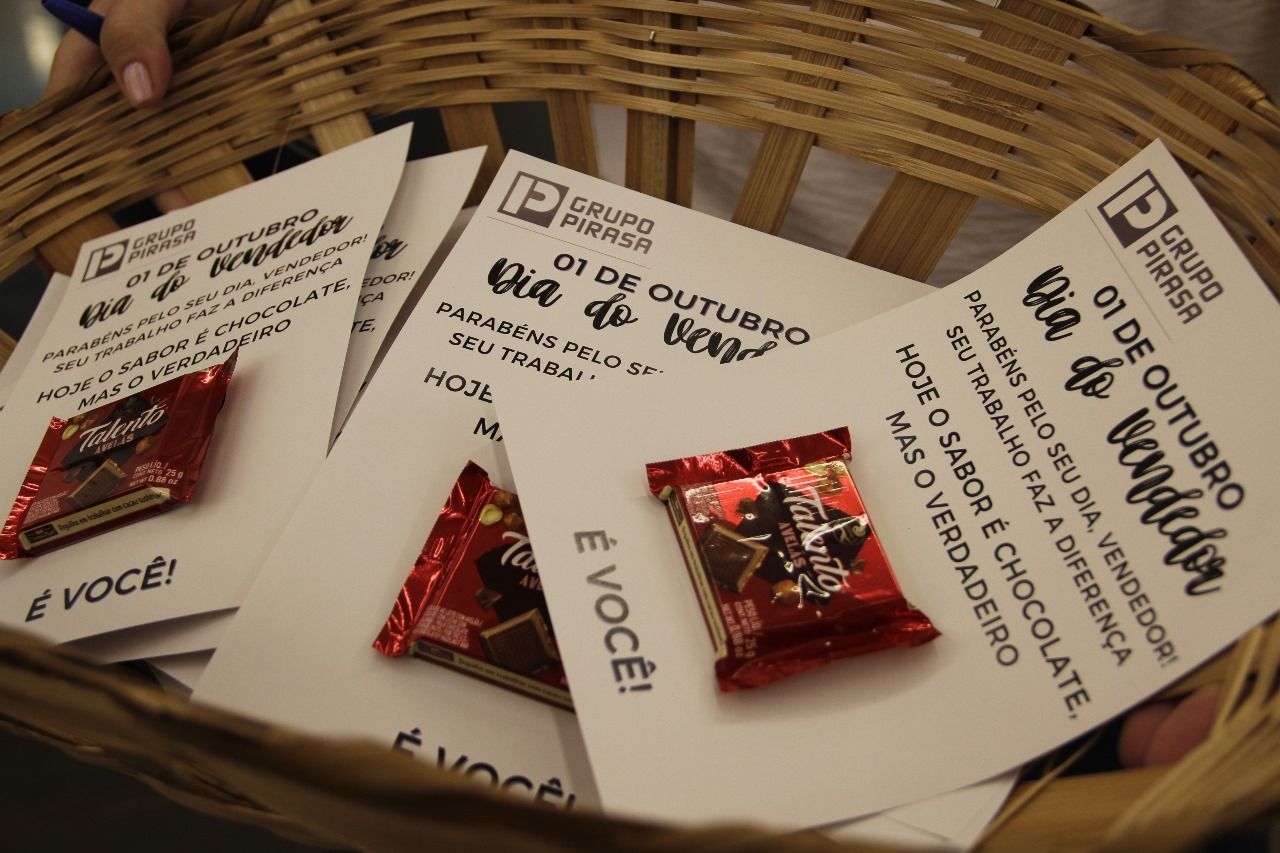 A woven basket holding white cards with text and chocolate bars. The cards read 