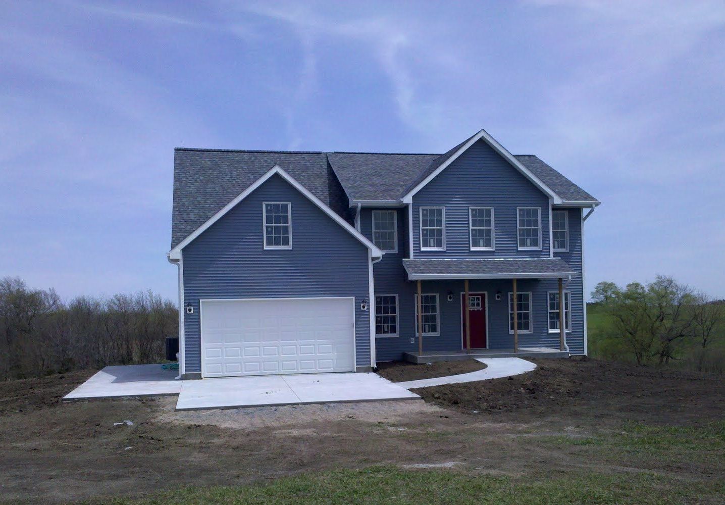A blue house with a white garage door and a red door