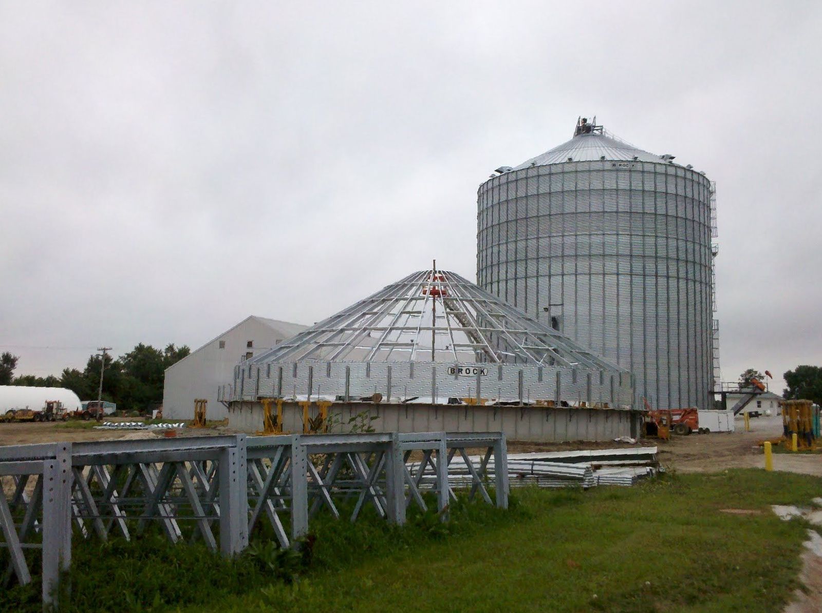 A large metal structure is being built on a farm