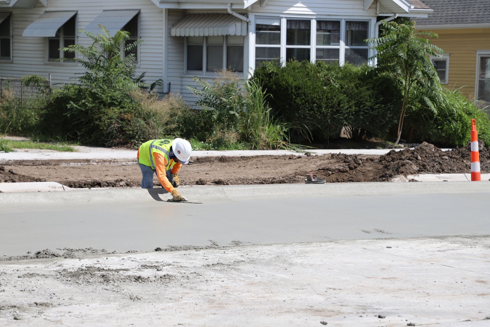CL Construction paving crew laying fresh concrete on Adams Street in Lincoln, Nebraska, as part of the LTU street rehabilitation project, with a Gomaco Paver machine spreading material and workers in high-visibility PPE gear
