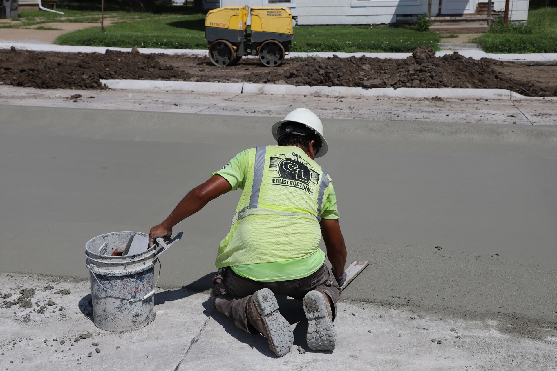 CL Construction paving crew laying fresh concrete on Adams Street in Lincoln, Nebraska, as part of the LTU street rehabilitation project, with a Gomaco Paver machine spreading material and workers in high-visibility PPE gear.
