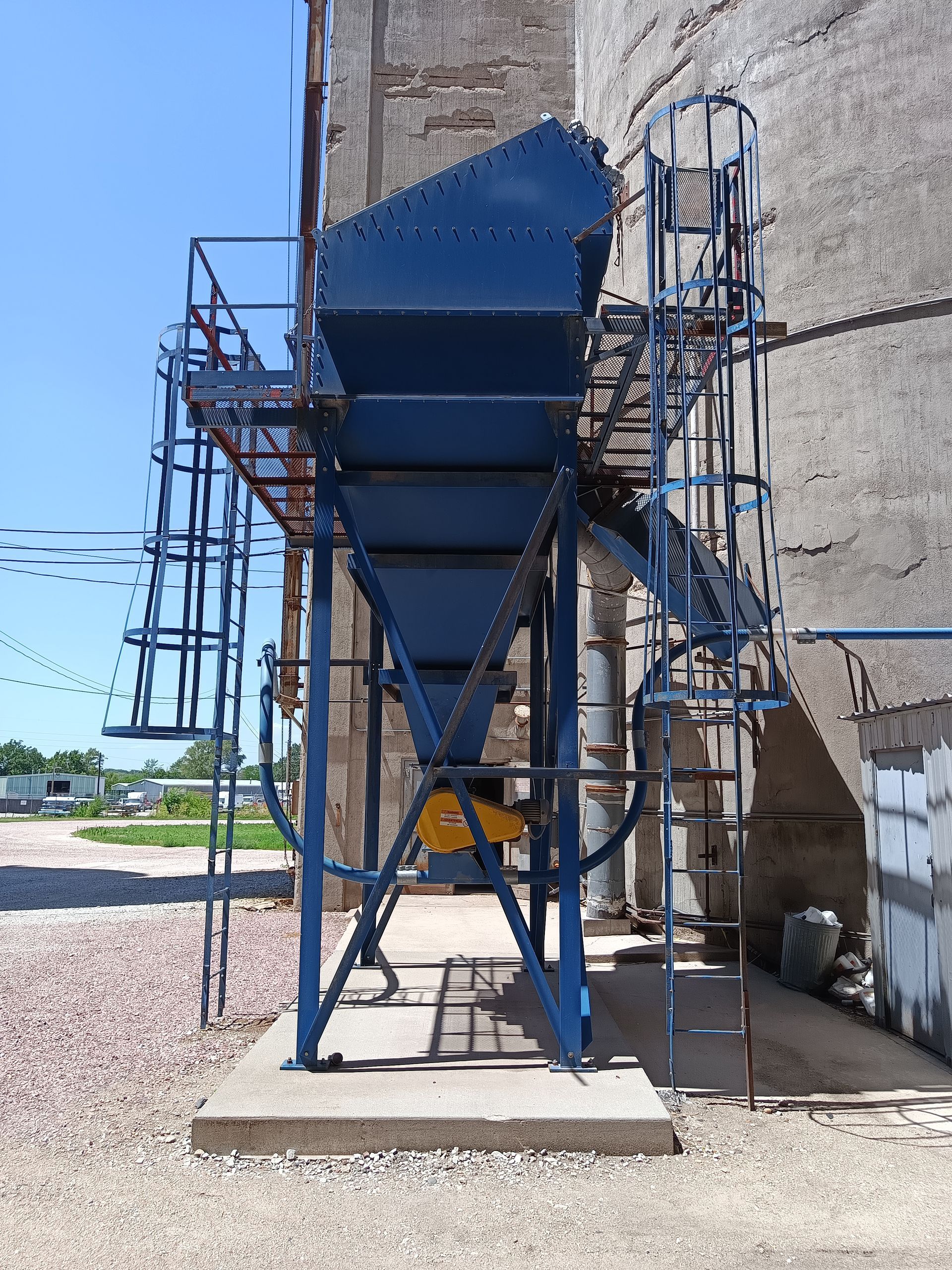 A blue machine with stairs leading up to it is sitting in front of a building.
