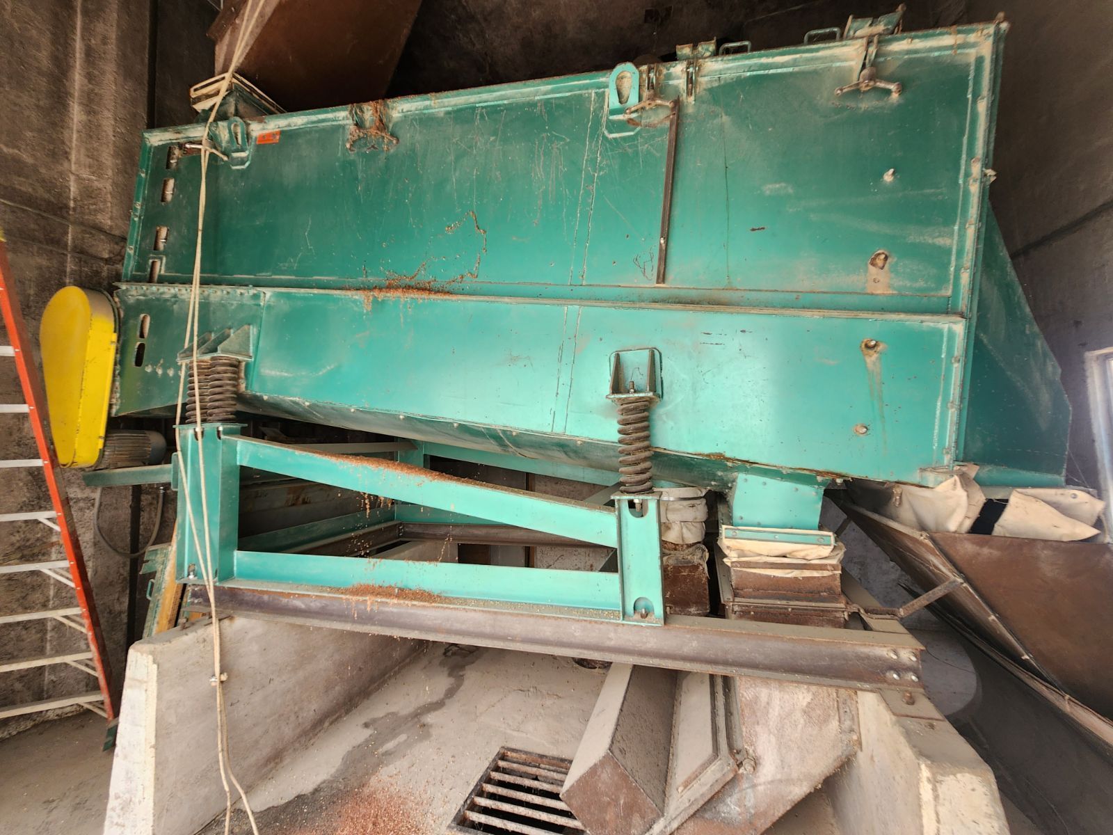 A green machine is sitting in a room next to a ladder.