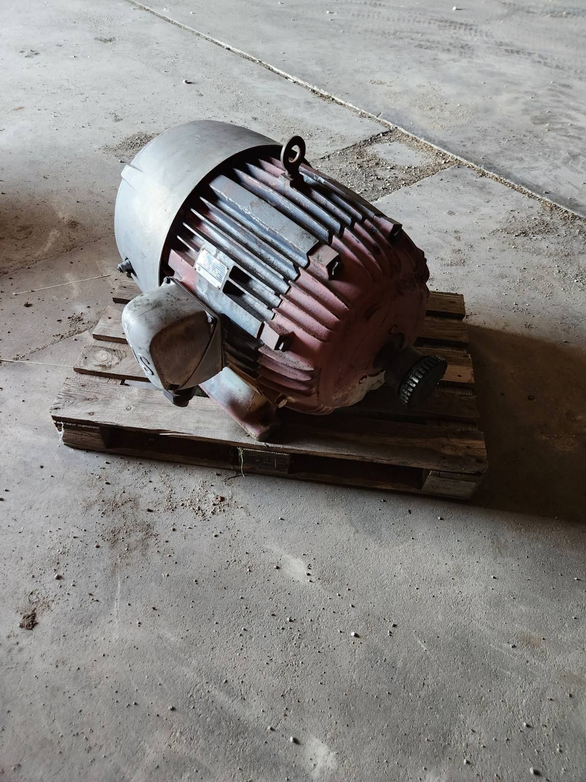A large motor is sitting on top of a wooden pallet.