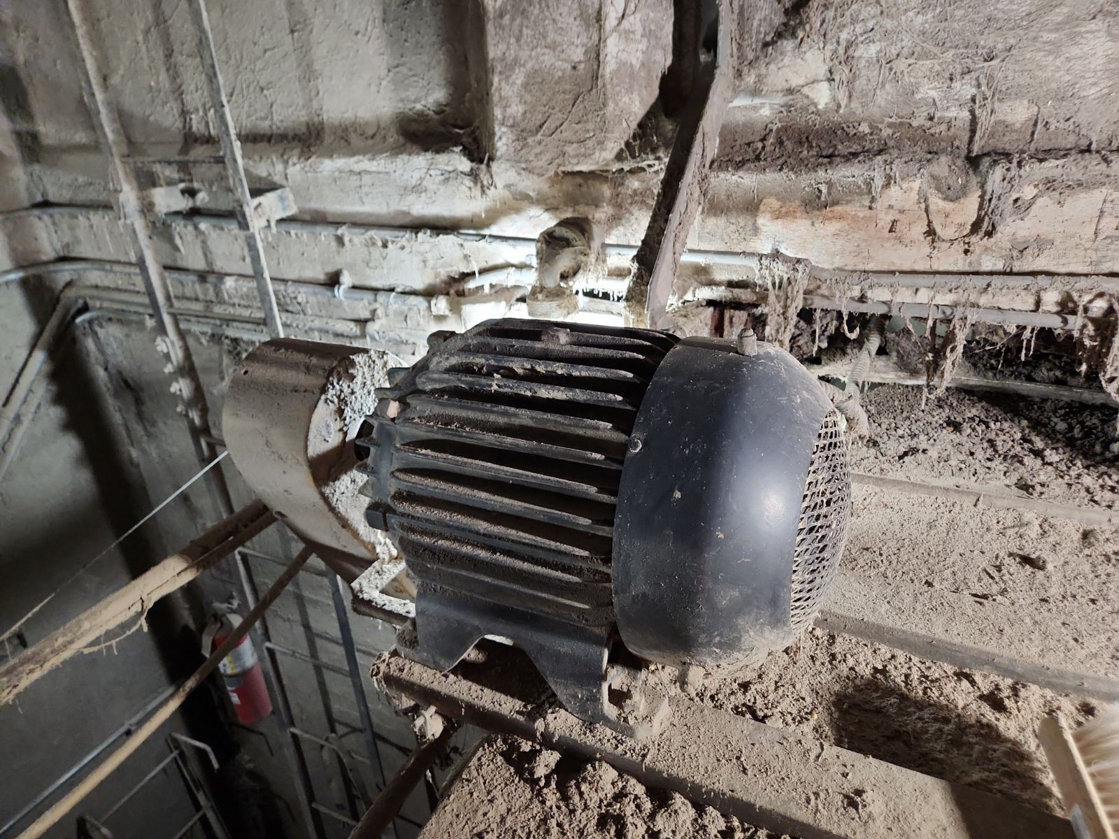 A large black motor is sitting on top of a pile of dirt.