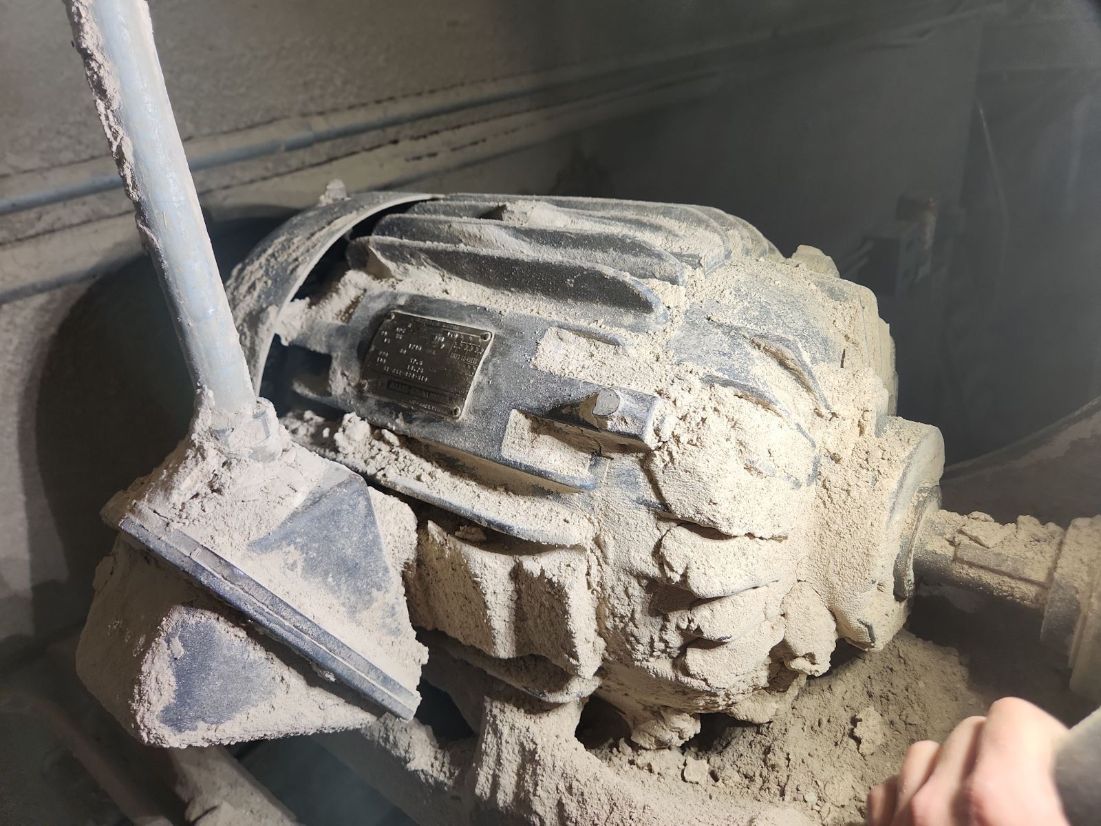 A person is cleaning a dirty motor with a shovel