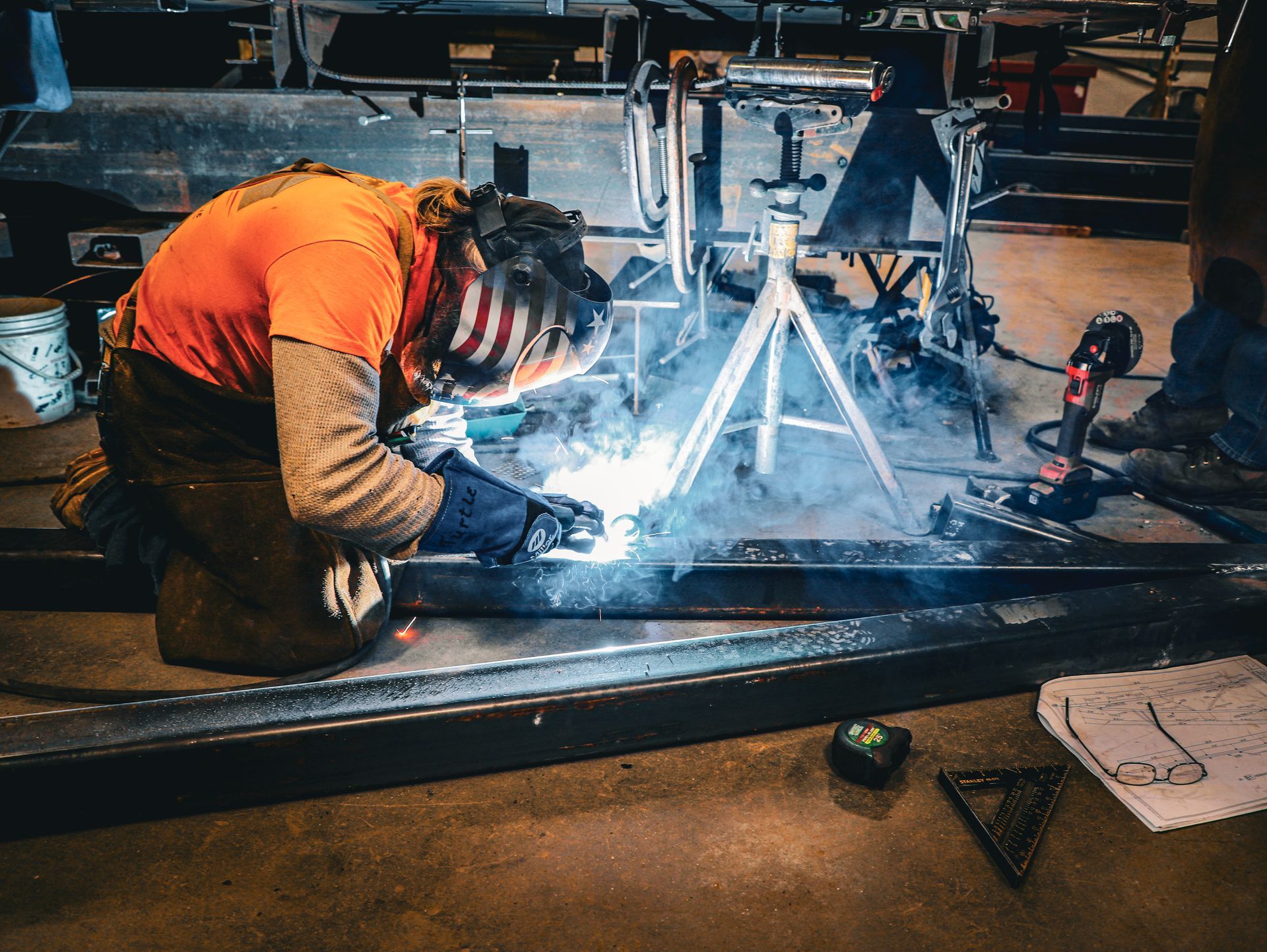 A man is welding a piece of metal in a factory.