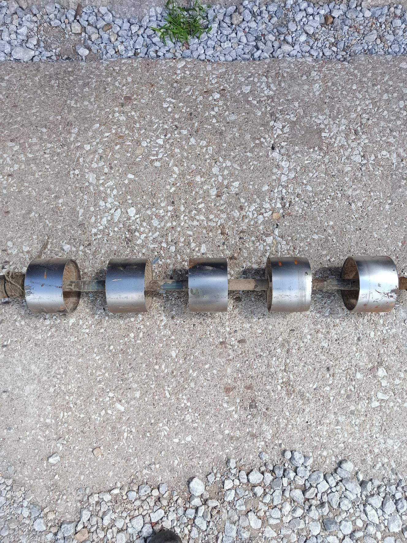 A row of metal pipes sitting on top of a gravel road.