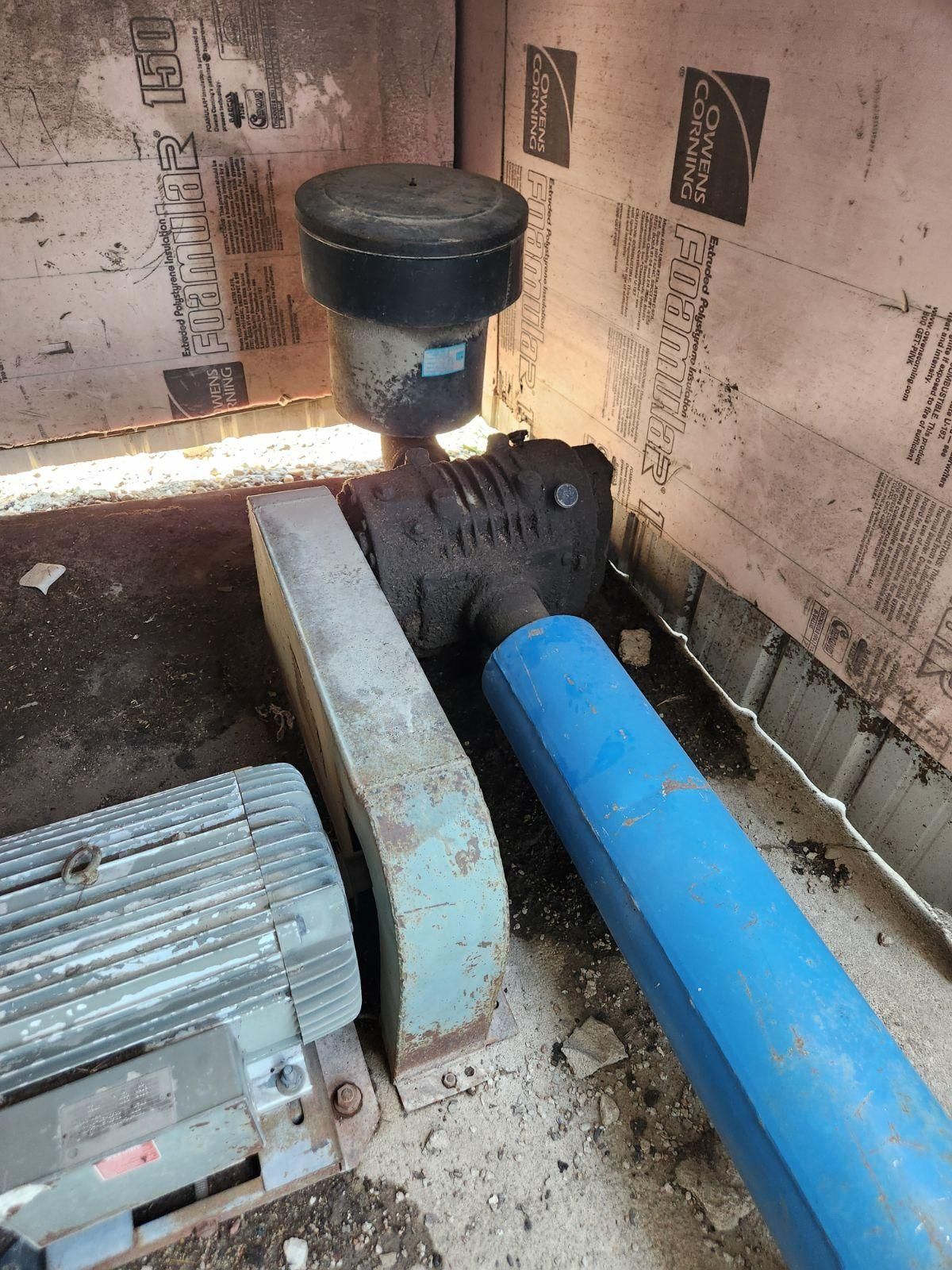 A blue pipe is connected to a machine in a room.