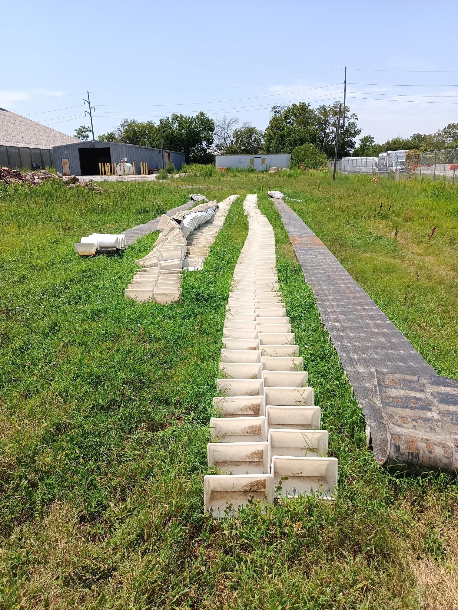 A row of concrete pipes are lined up in a grassy field.