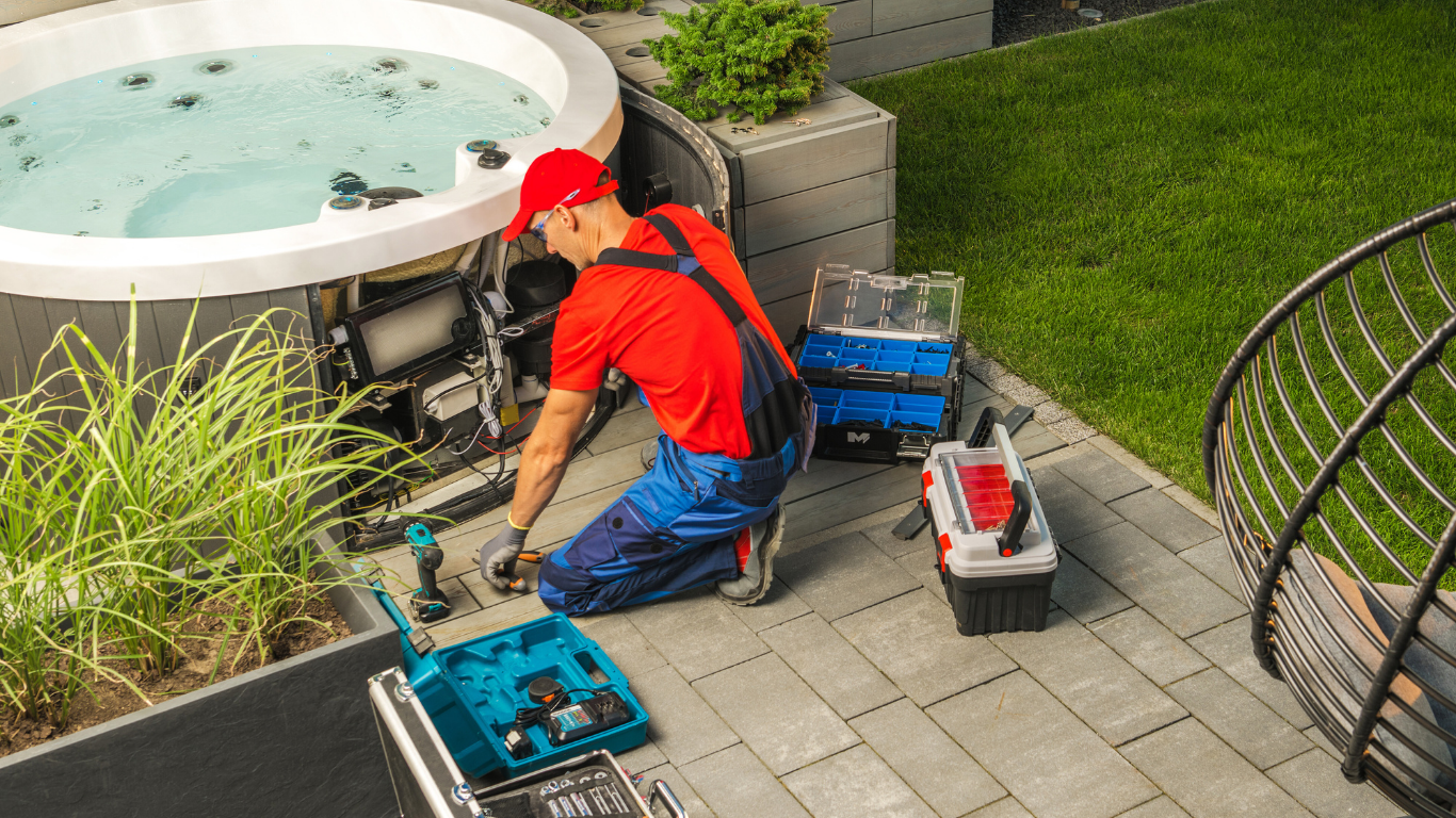 Person in red shirt and overalls repairing a hot tub outdoors, surrounded by tools.