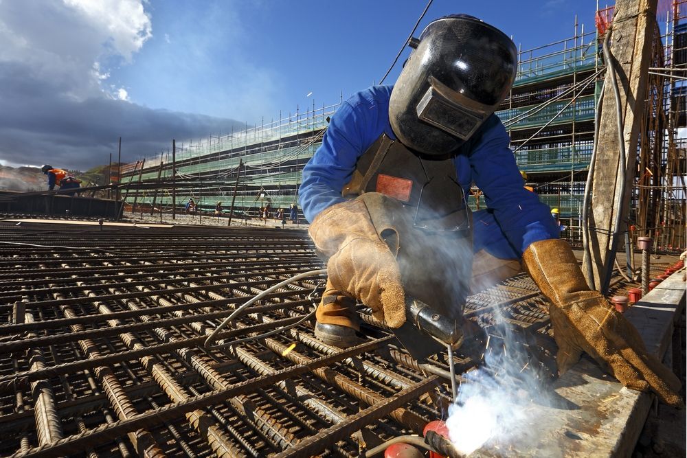 A Man Wearing a Welding Helmet is Welding a Metal Structure — Sun City Sheetmetal In Townsville, QLD